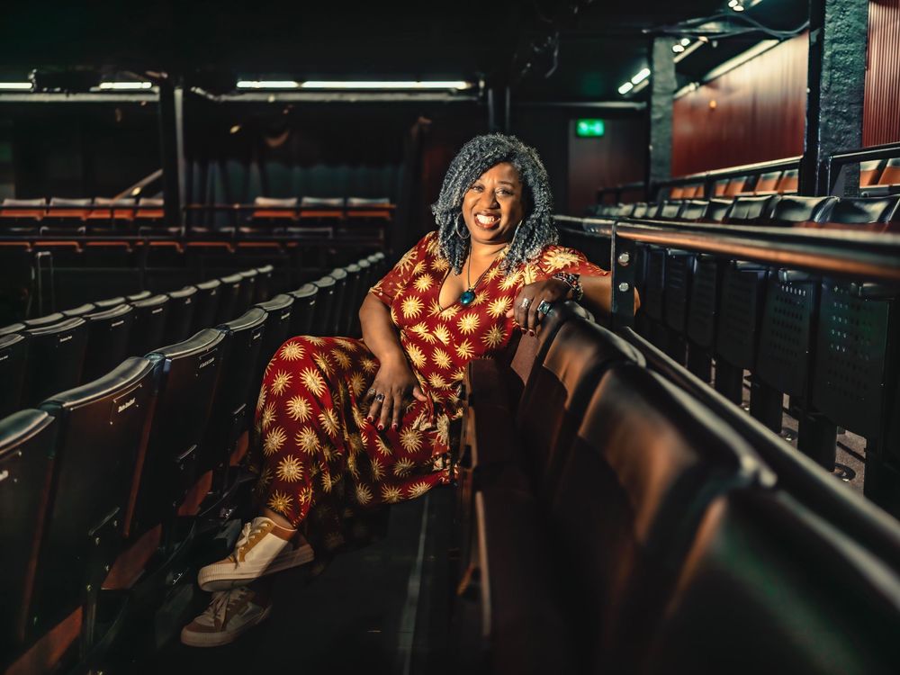 A dancer in a red polka dot dress leans back gracefully across bowling alley lanes in dramatic lighting.