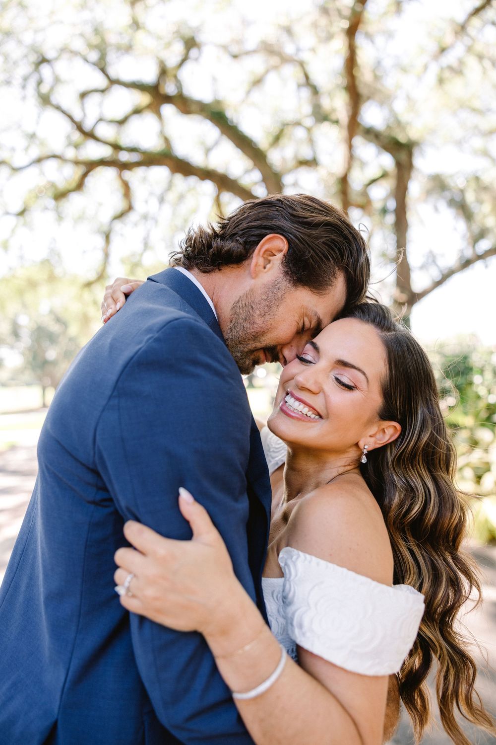 Intimate romantic moment captured outdoors with natural sunlight filtering through trees.