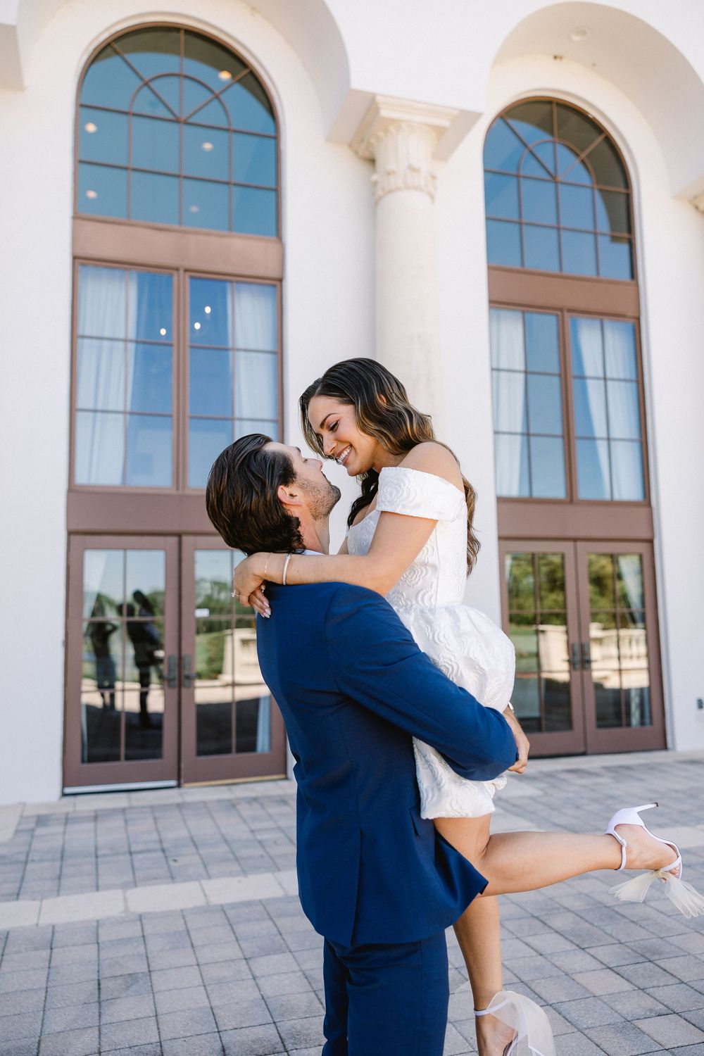 Playful embrace in front of an elegant building with classical architecture.