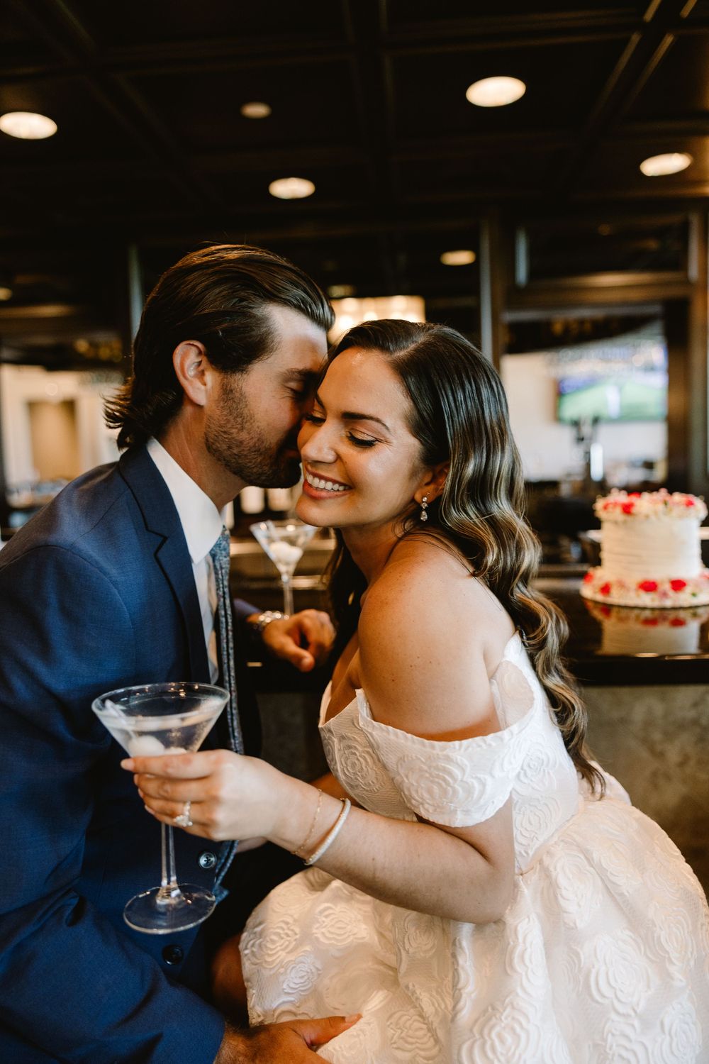 A couple shares an intimate moment while holding wine glasses in an indoor venue.