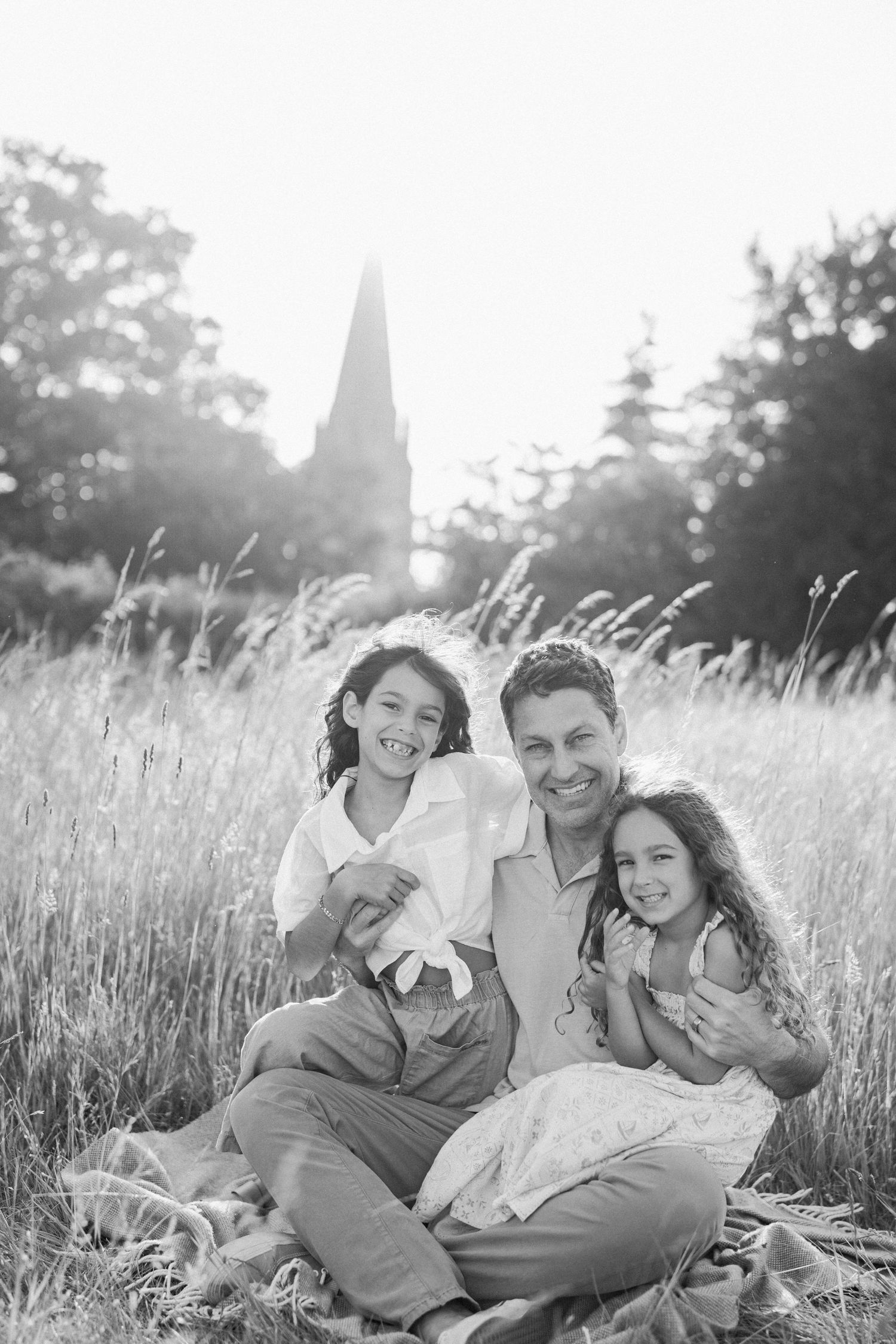 A casual family photoshoot in a scenic meadow during golden hour.