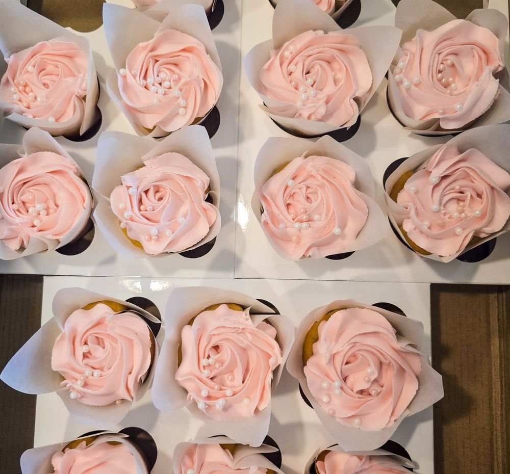 A sequence of delicate pink buttercream roses piped onto cupcakes in a baking tray shows decorating in progress.