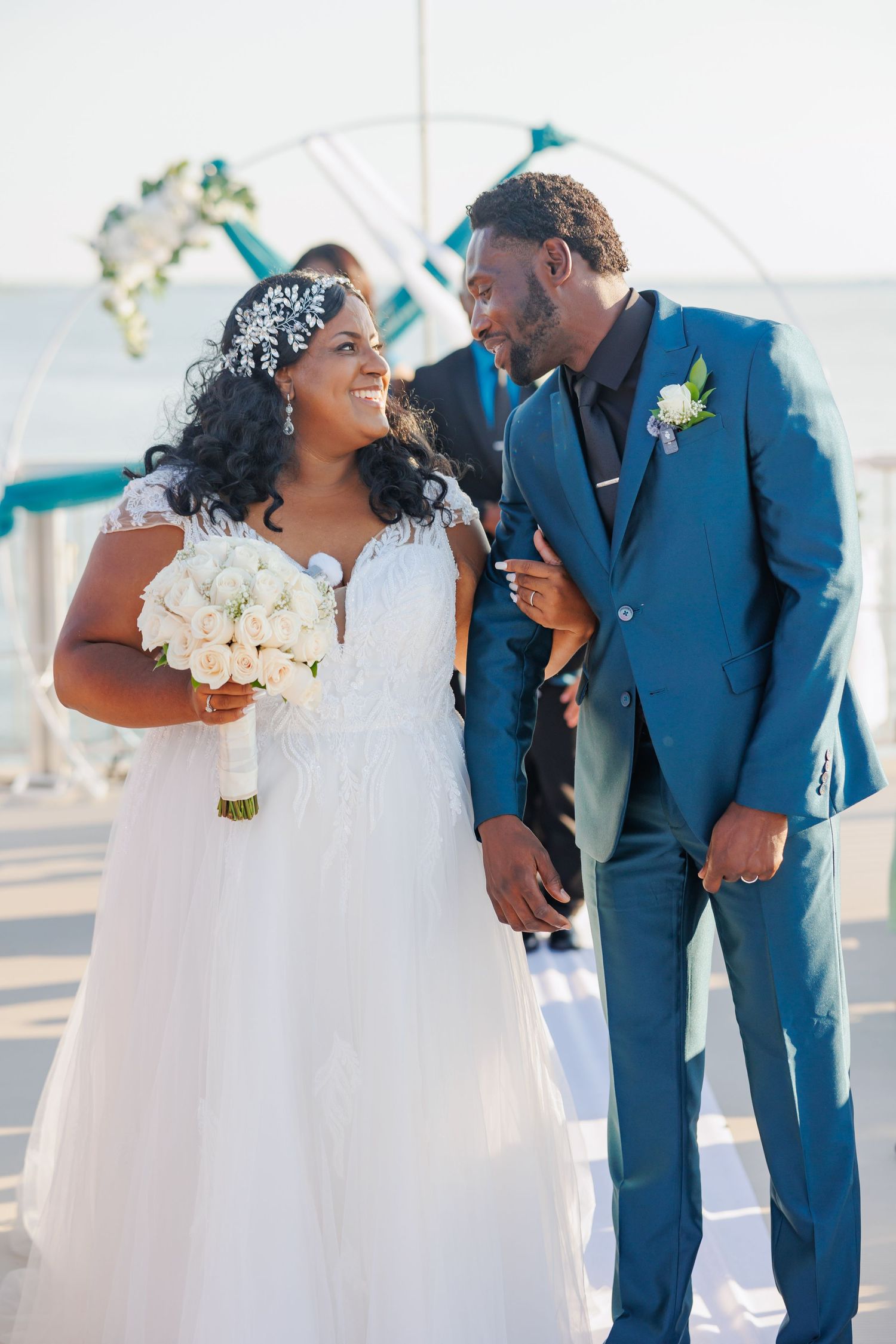 A couple shares joyful moments in formal wedding attire with the bride in white and partner in navy blue suit. Wedding at Rockwall Harbor