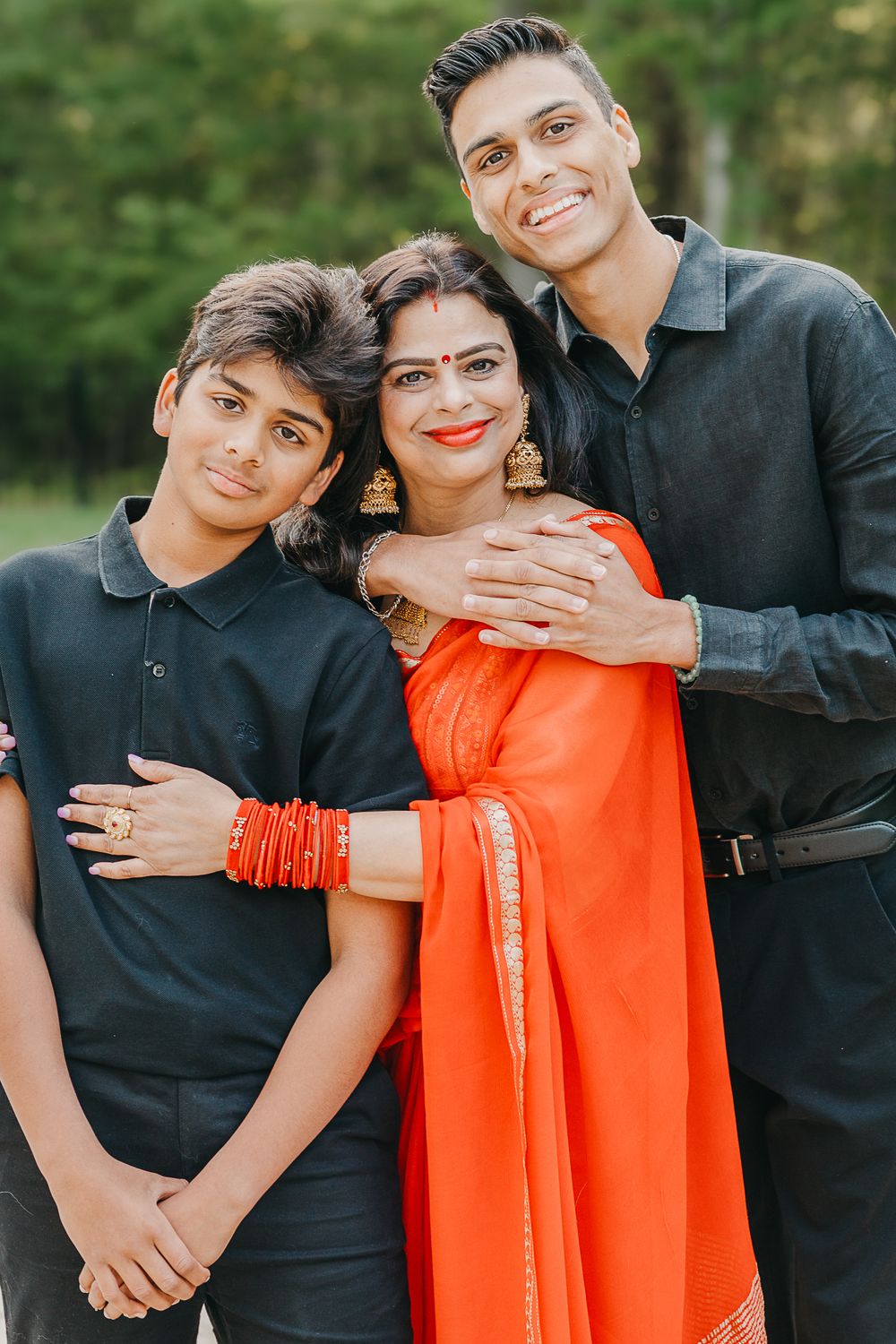 Three people in black and orange formal attire pose together in an outdoor photo sequence.
