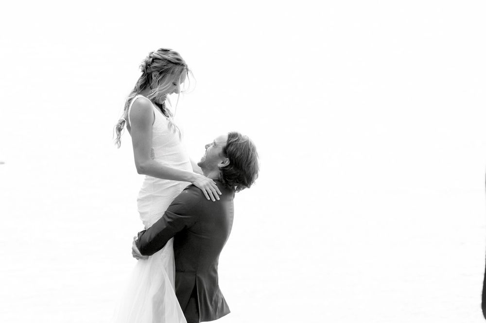 A romantic black and white portrait of a couple in an intimate embrace, with one person lifting the other.