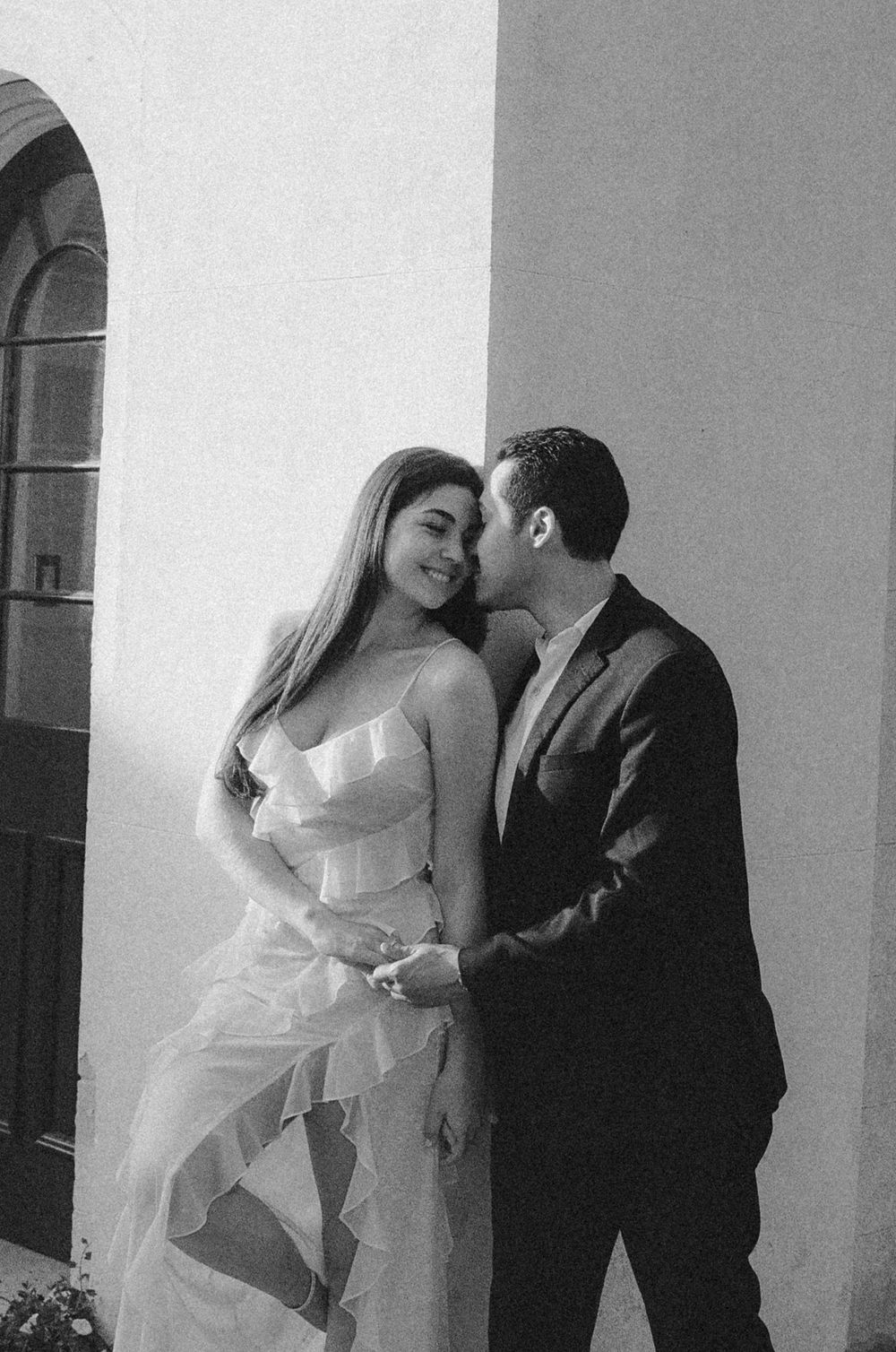 A romantic couple shares intimate moments in a sequence of wedding photos against a white wall.