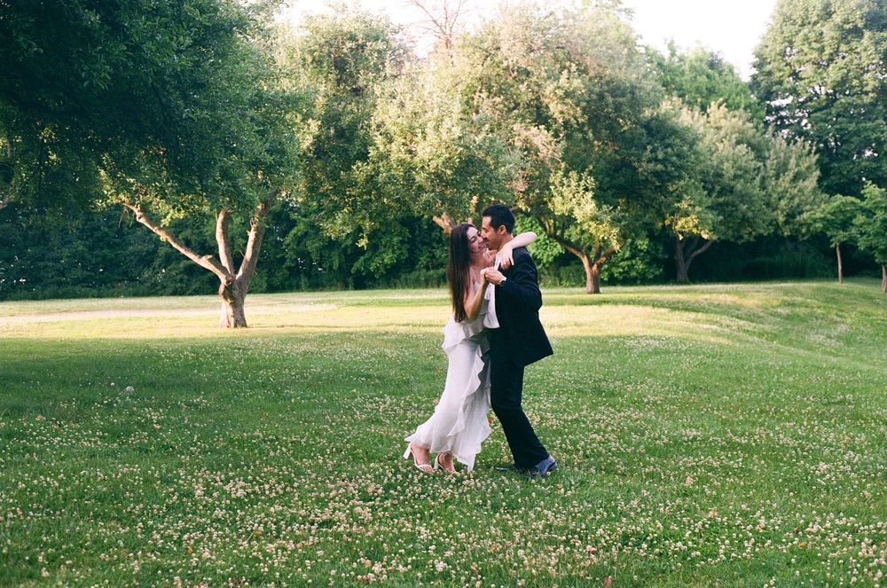 A romantic outdoor photo sequence showing movement and dance across a sunlit grassy meadow.