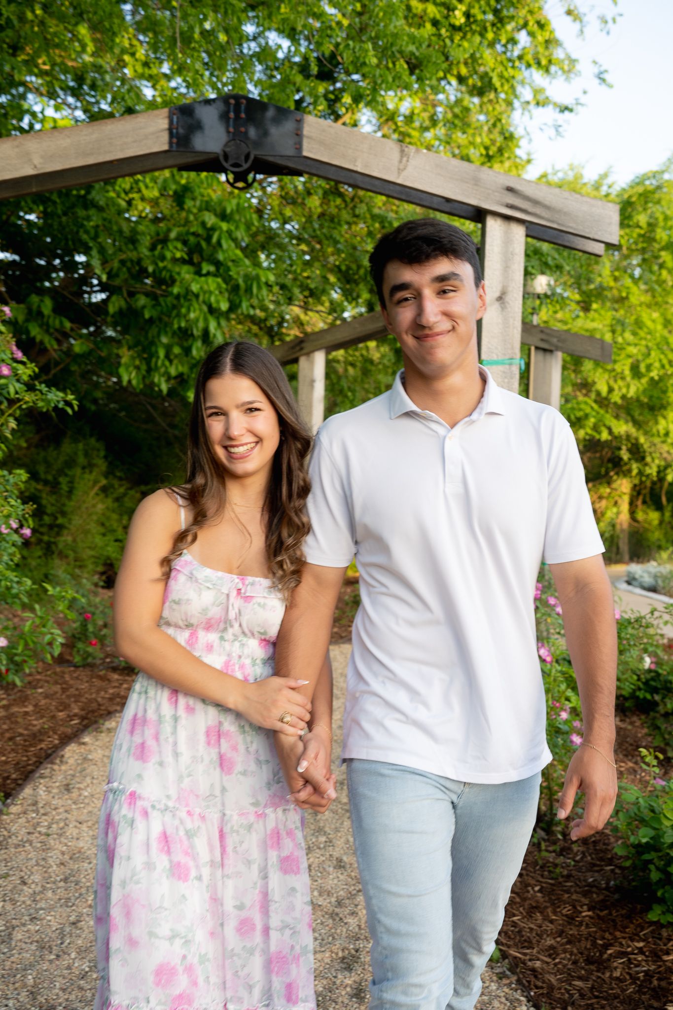Couple poses romantically under sprawling oak tree branches on campus path.