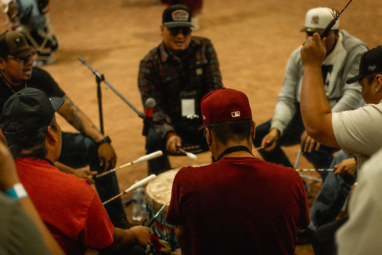Musicians and drummers seated in a circle performing traditional Native American music.