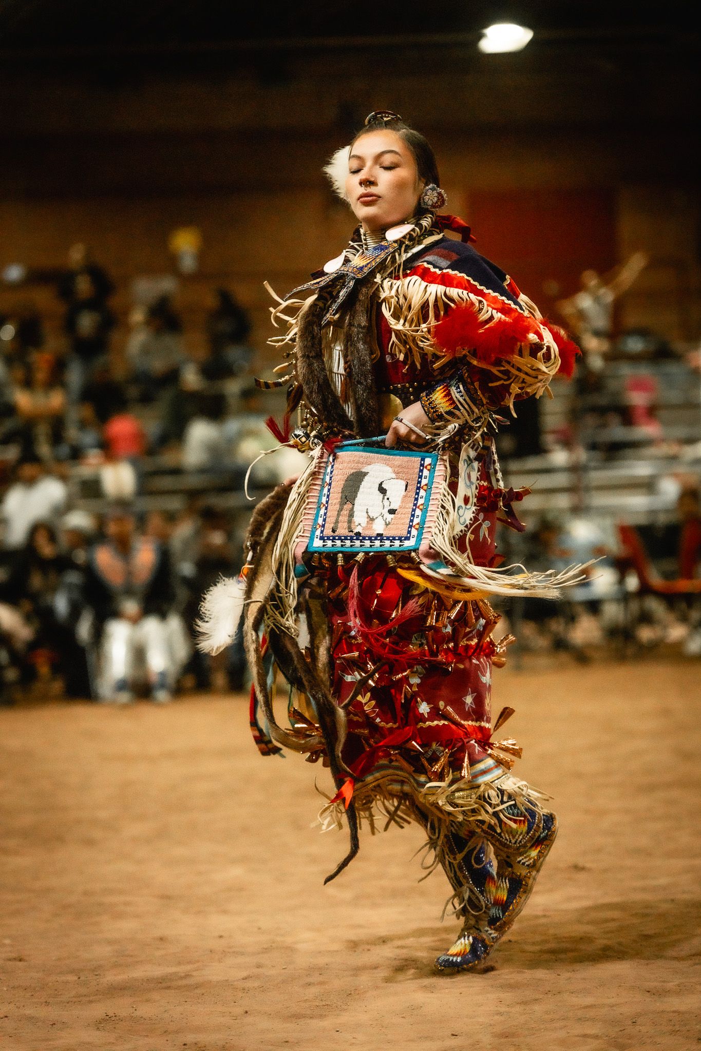 Traditional Native American dancer performing in vibrant red regalia at a powwow.