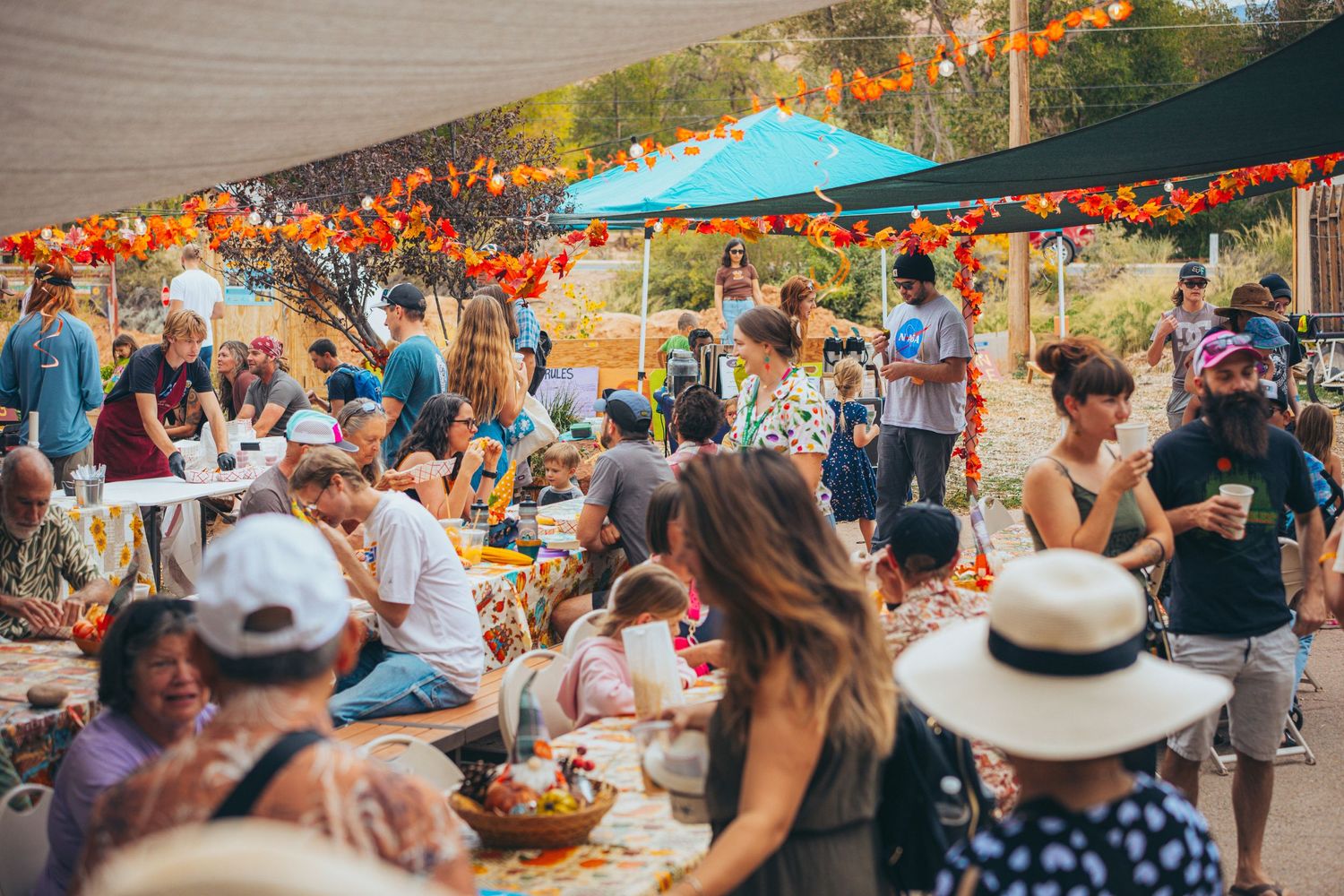 Outdoor festival gathering with people dining under colorful canopies.