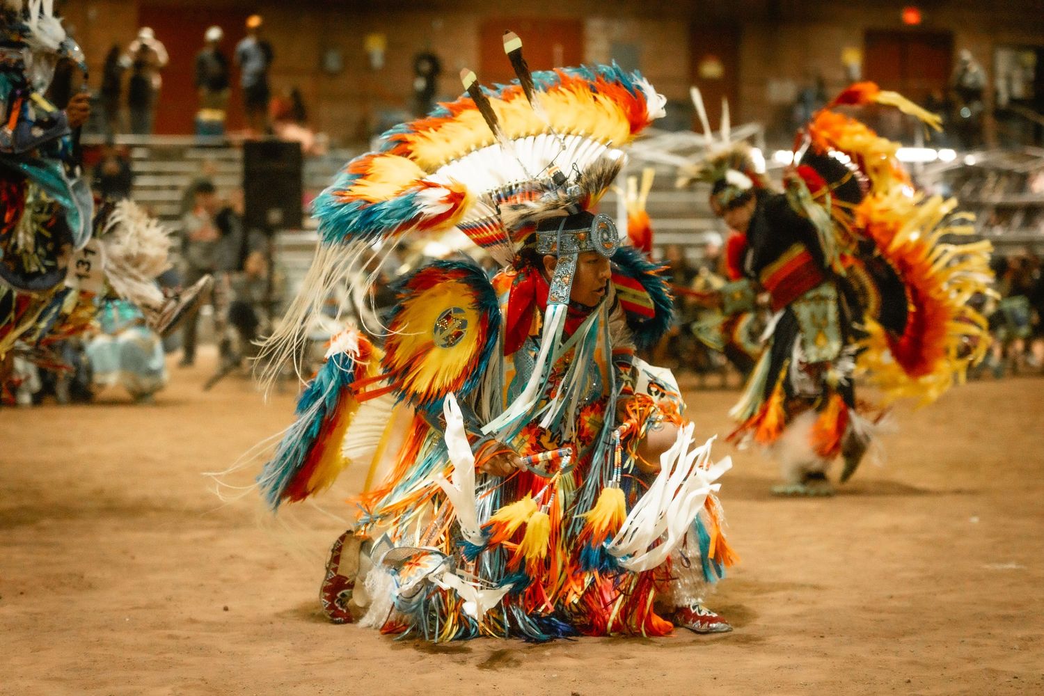 Vibrant feathered headdresses sway during a traditional Native American pow wow dance performance.