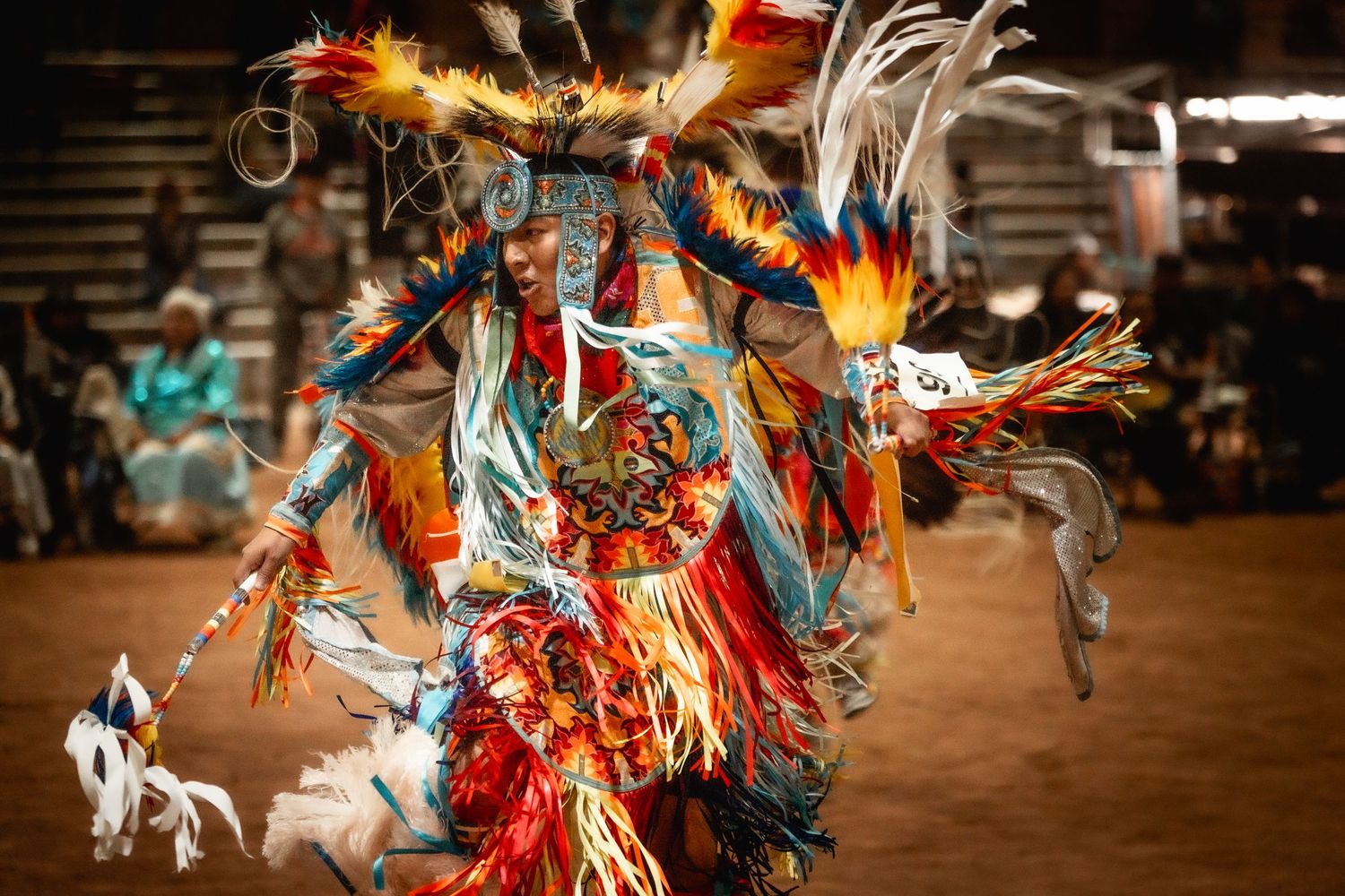 Dancers in full traditional regalia performing at a Native American powwow ceremony.