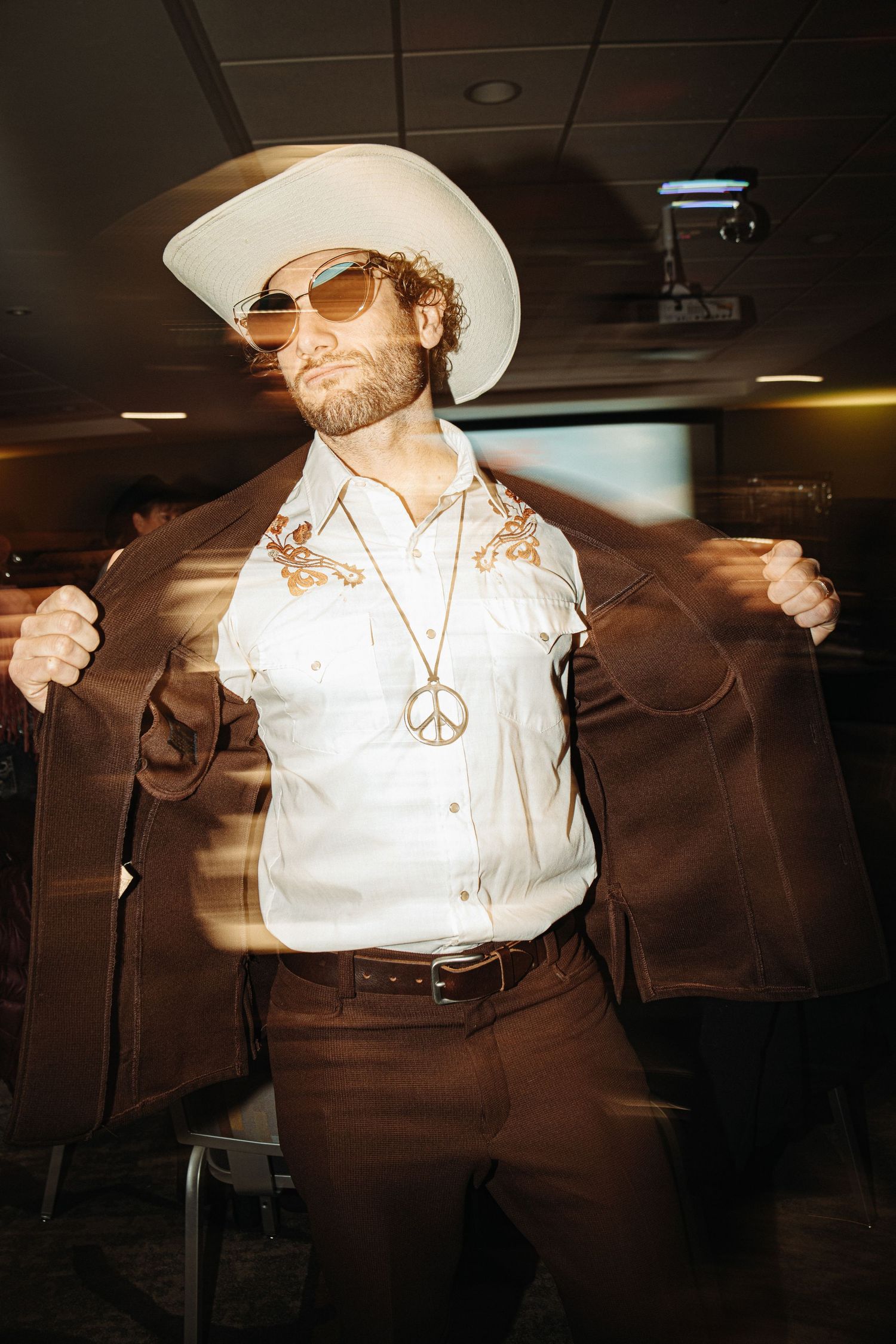 Retro-styled photo of someone in western wear striking a dynamic pose indoors.