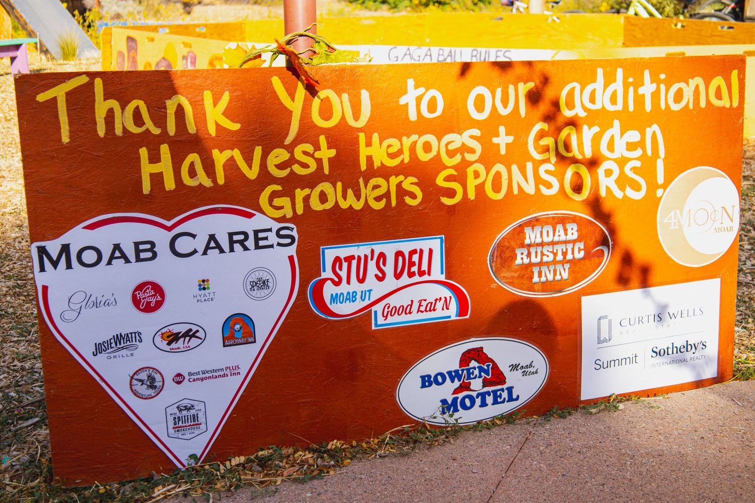 Orange thank you sign displaying local business sponsors and harvest heroes logos.