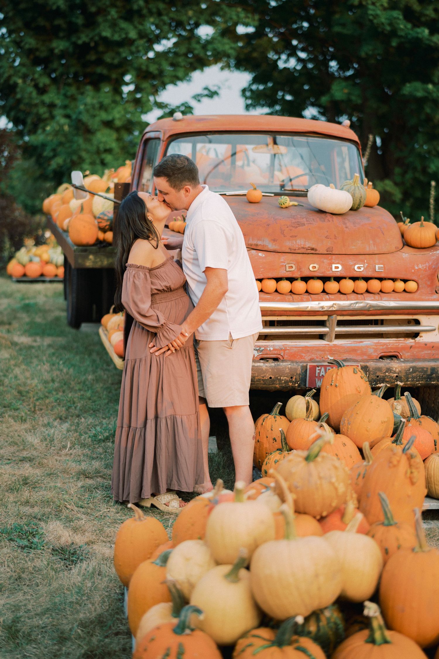 A romantic autumn moment by a vintage orange truck surrounded by pumpkins.