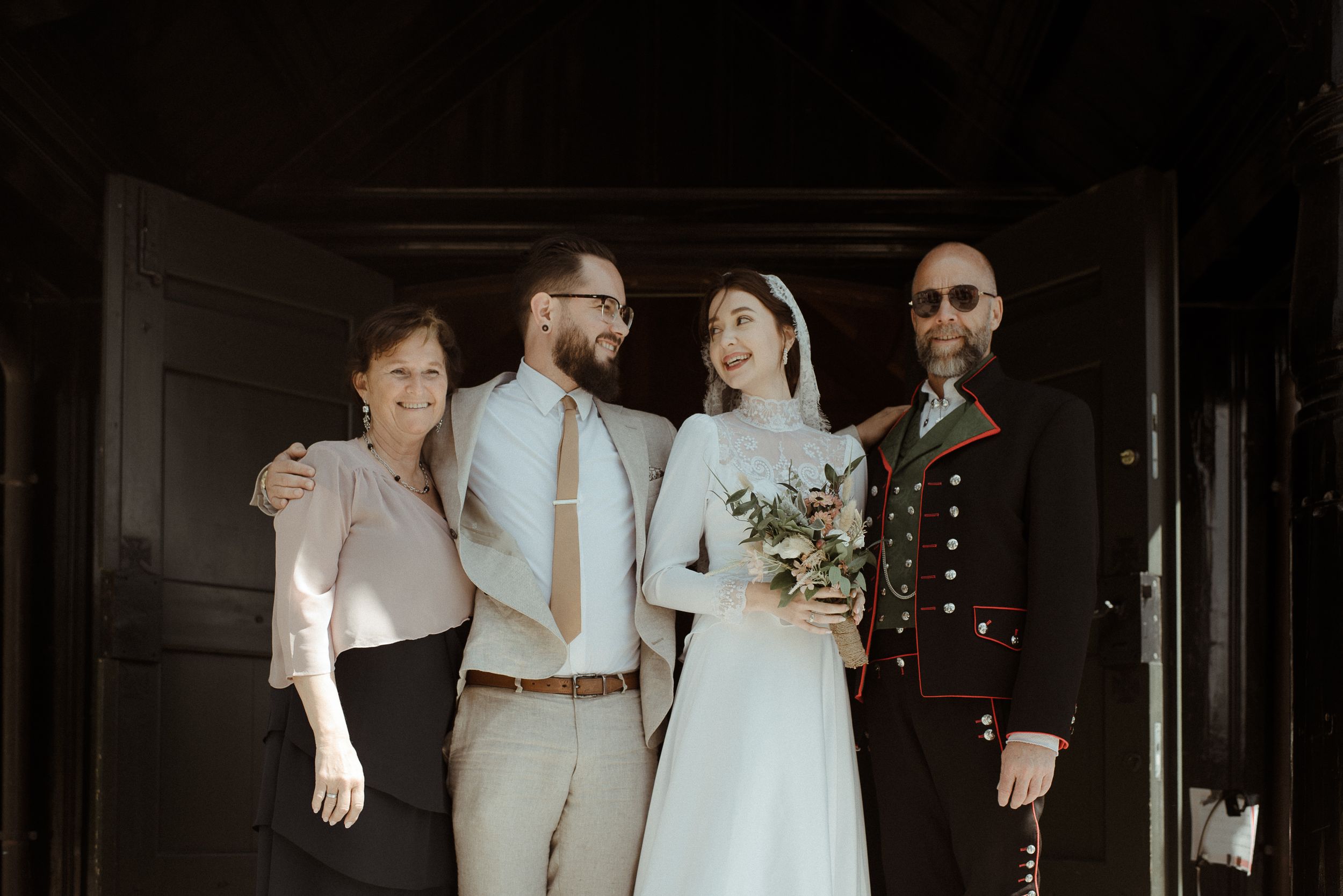 Wedding party members pose together after ceremony in formal attire.