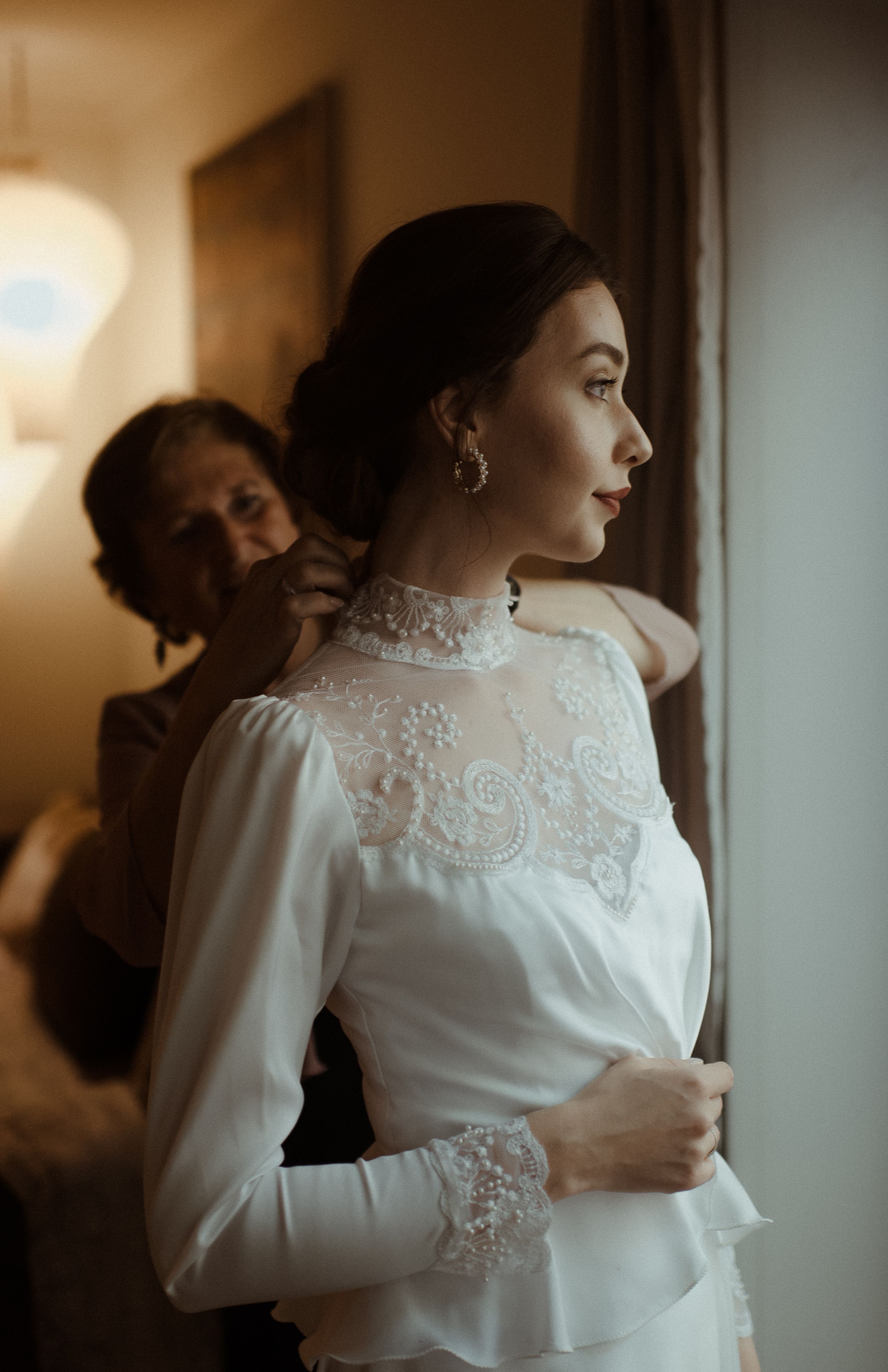 Vintage-style wedding dress with high neck lace detail and long sleeves captured in warm lighting.