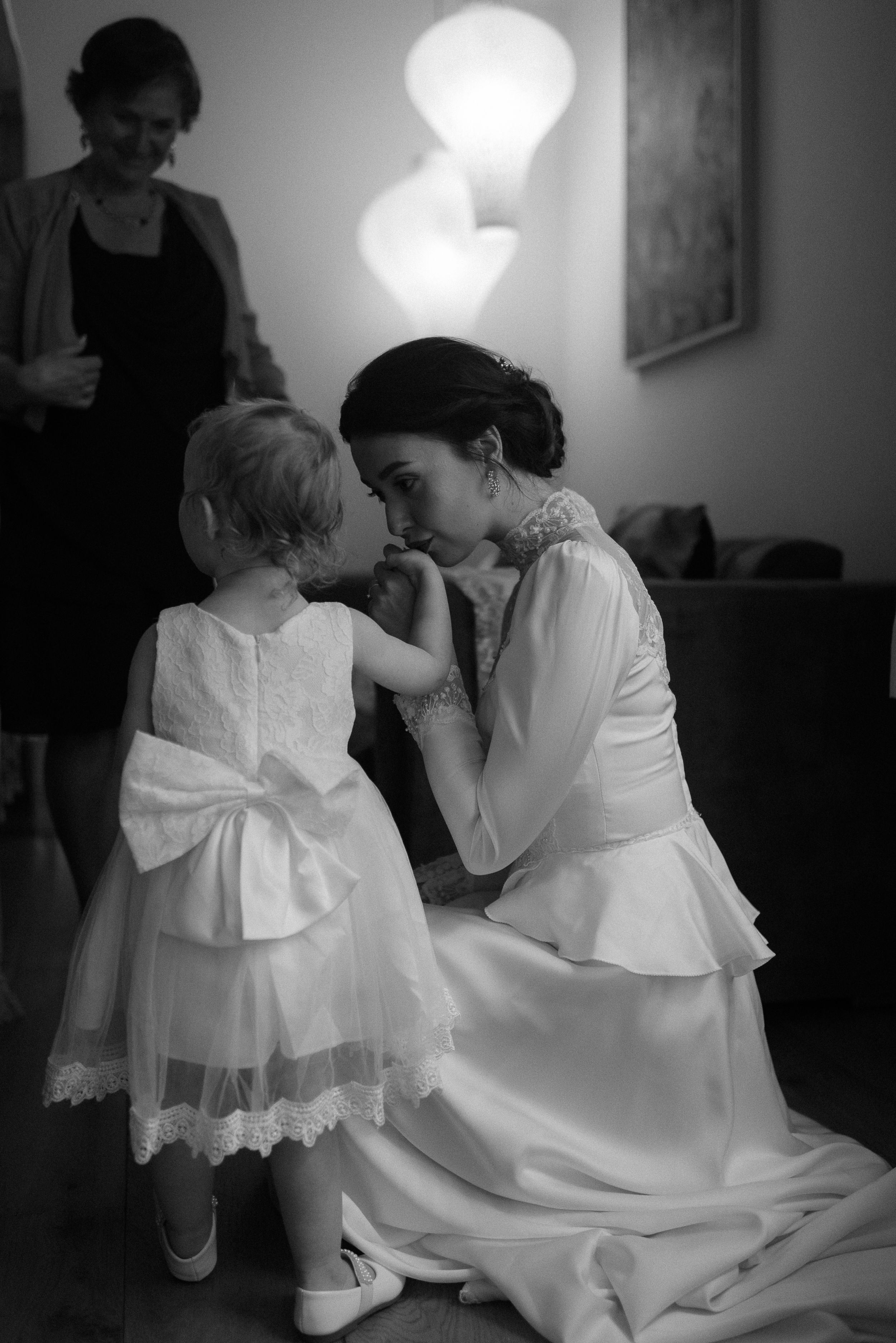 Sweet moment between bride in white dress and small child in formal attire.