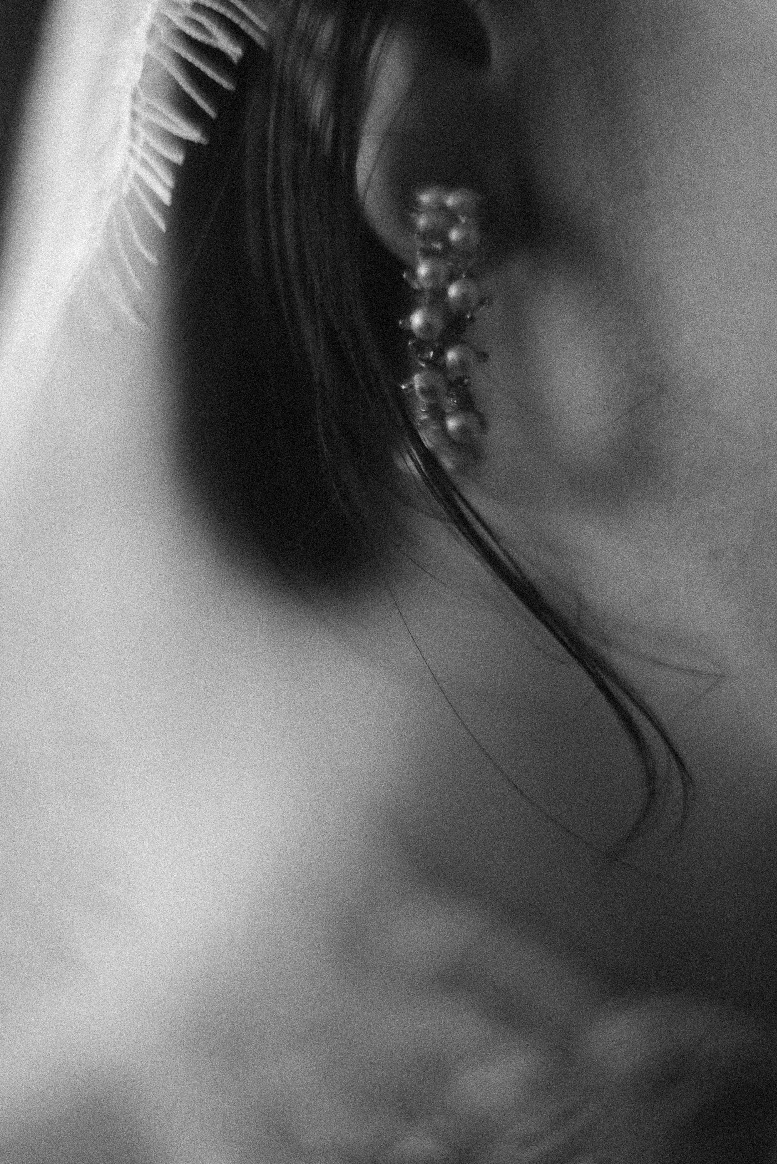 Close-up black and white photo of an ornate pearl earring against soft focus background.