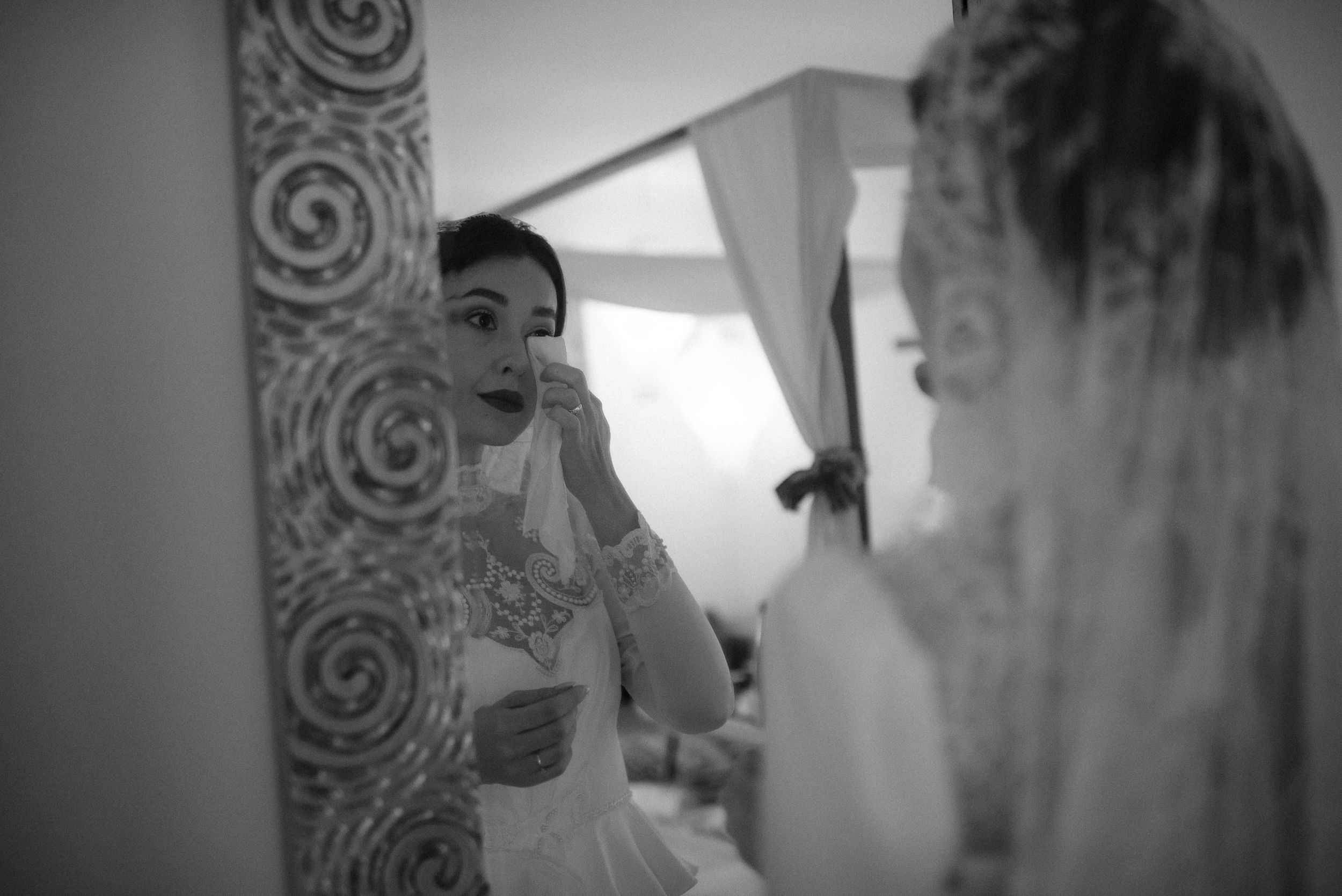 Reflection of bride in mirror while getting ready for wedding ceremony.