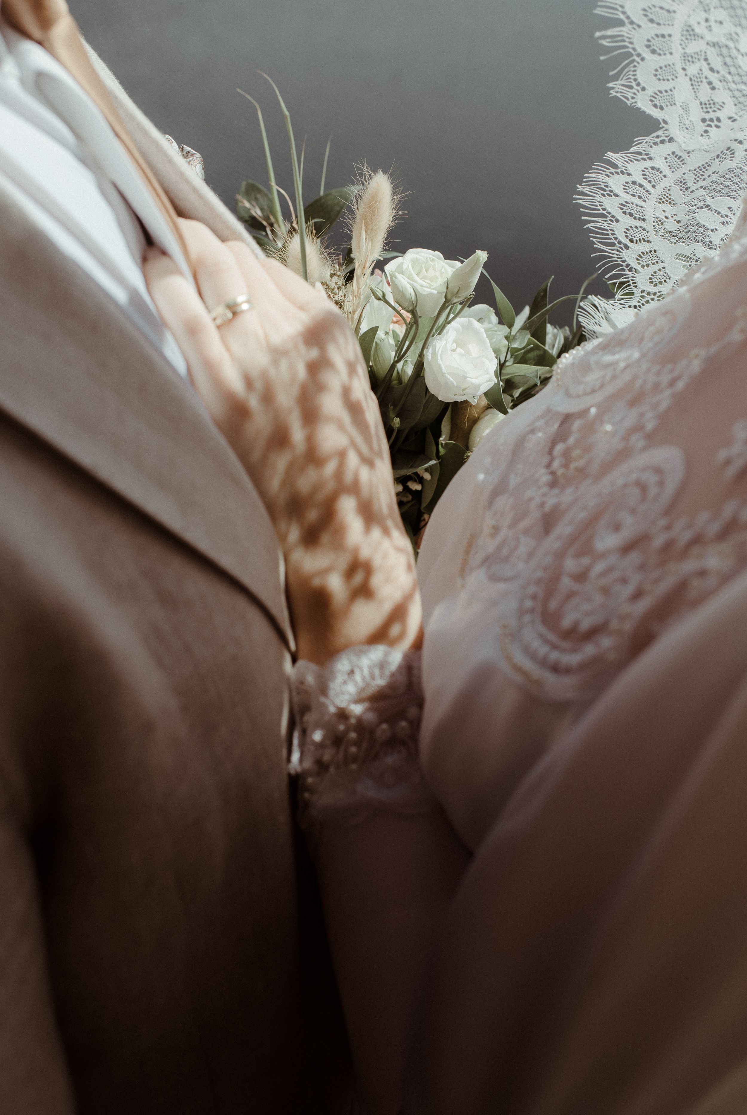 Close-up detail of wedding bouquet nestled between formal attire.