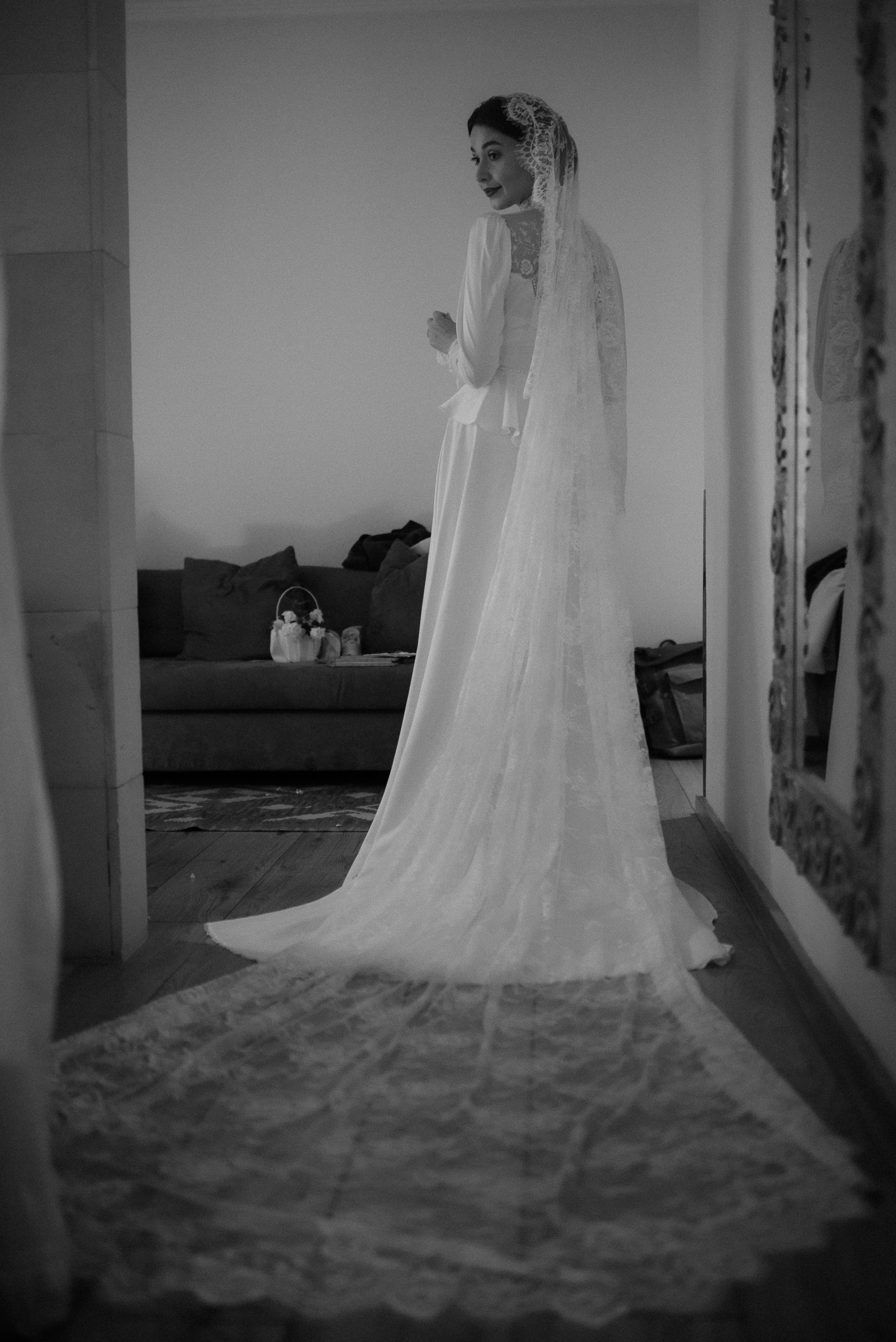 Full-length view of flowing wedding dress with cathedral veil in dramatic black and white.