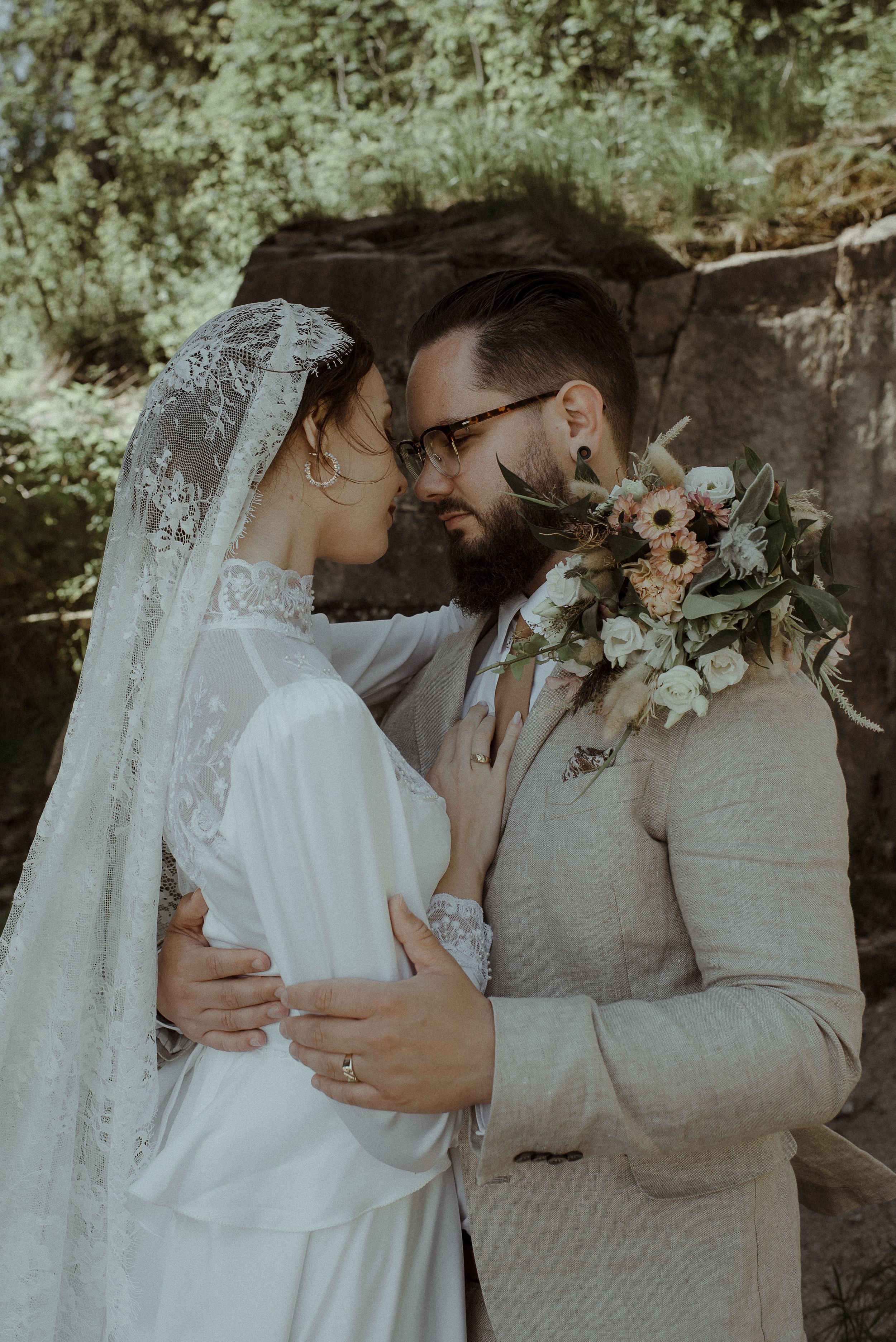 An intimate wedding portrait with a delicate bouquet and flowing lace veil.