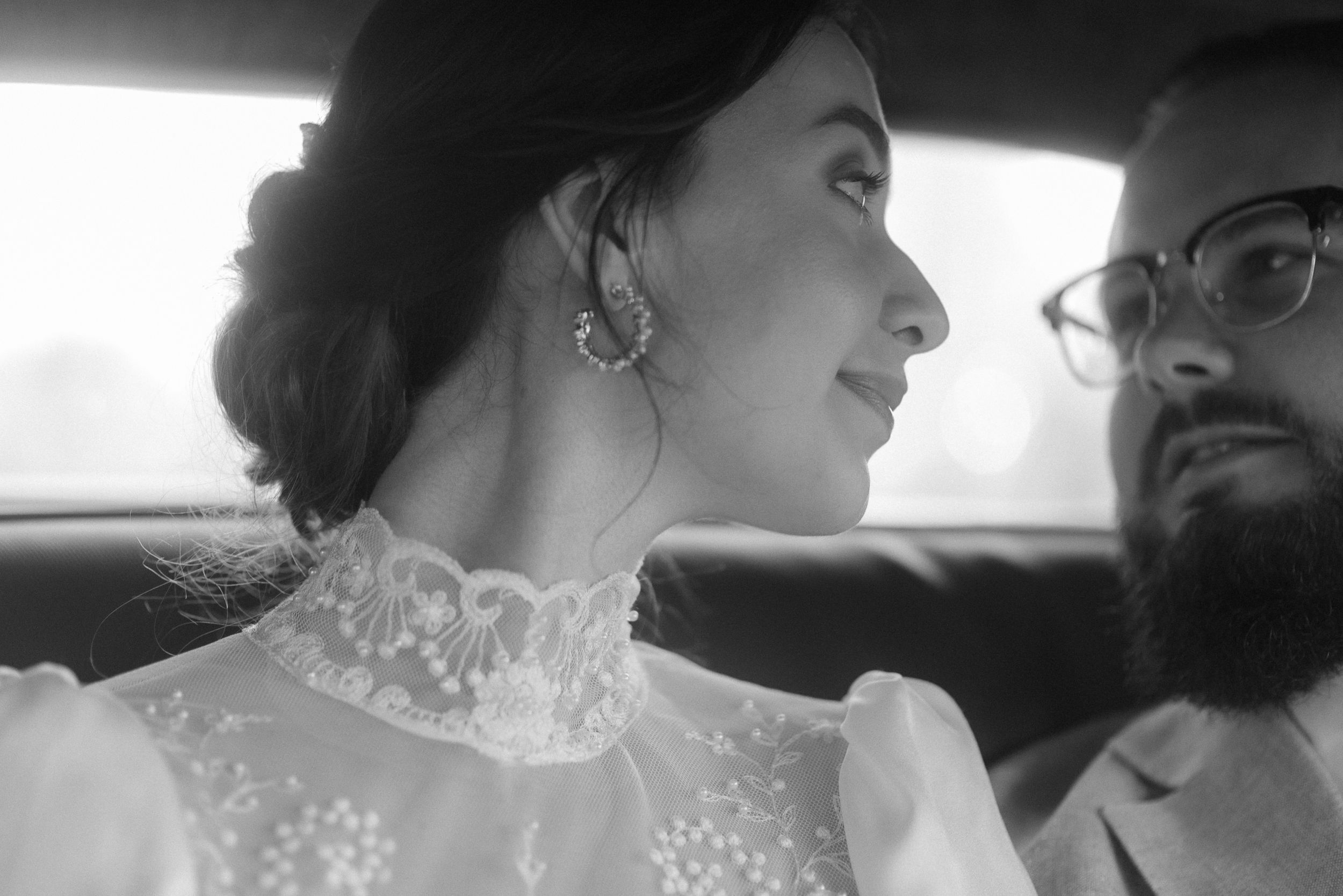 A romantic black and white portrait taken inside a classic car.