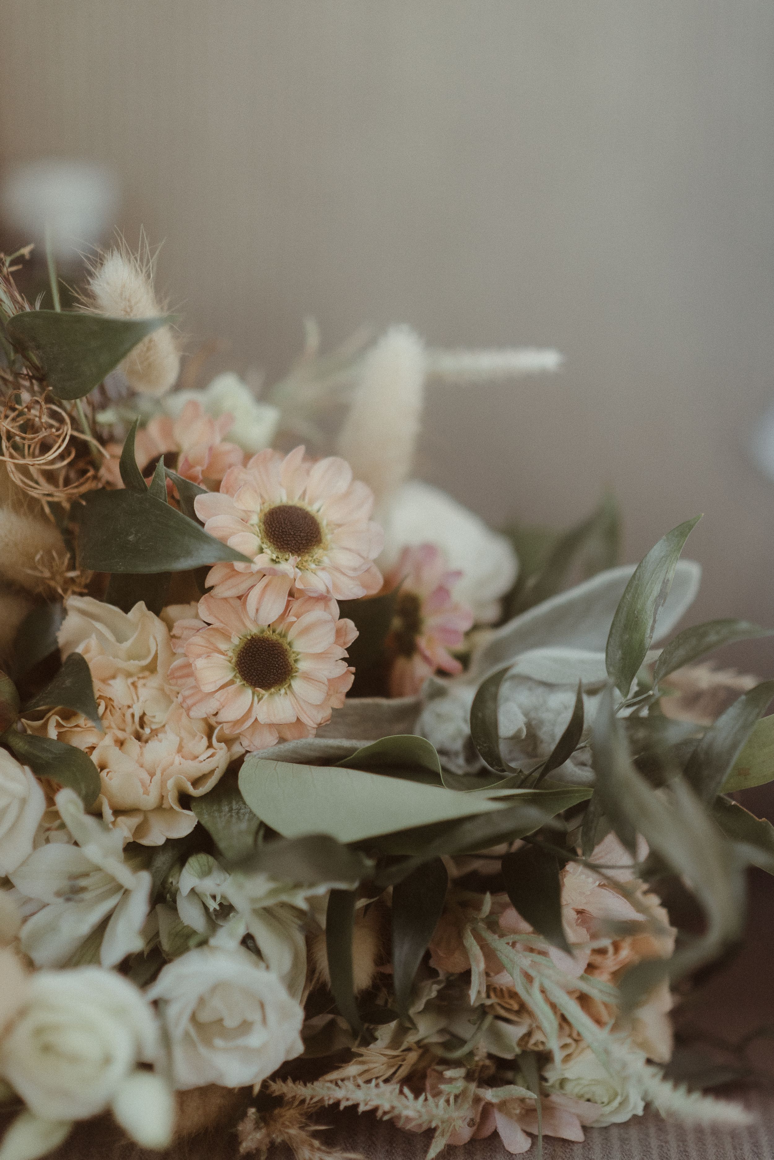 A soft focus wedding bouquet with pale pink daisies and roses with eucalyptus leaves.