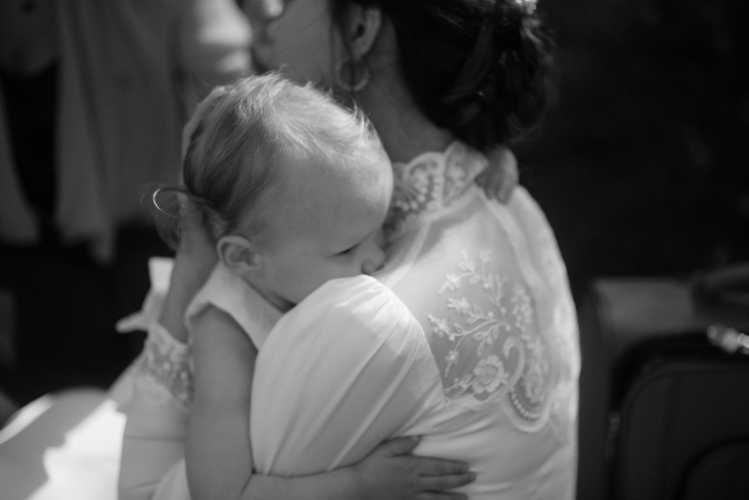 A tender black and white moment showing a baby resting on a shoulder.