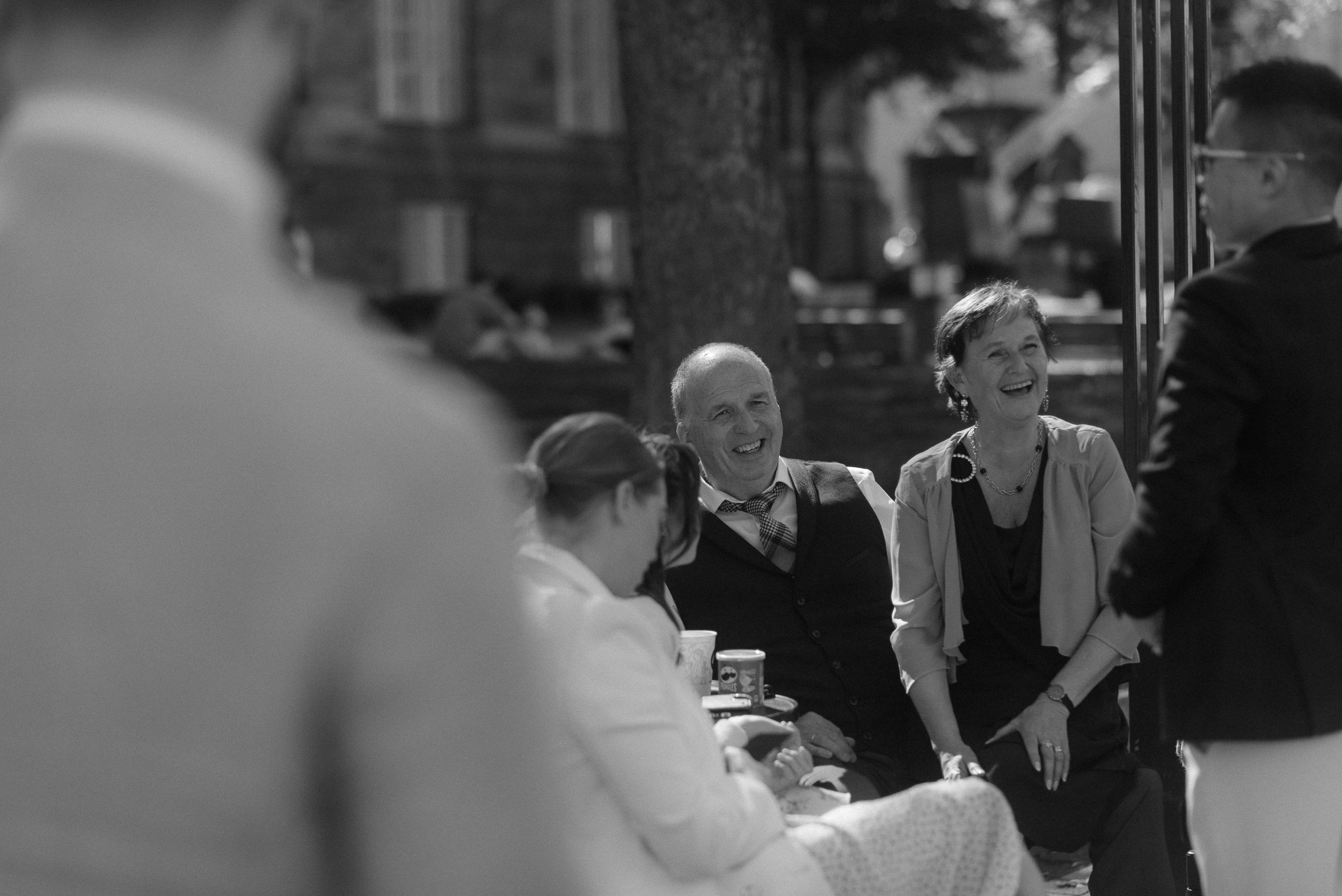 A casual outdoor gathering shows people conversing during a social event in black and white photography.