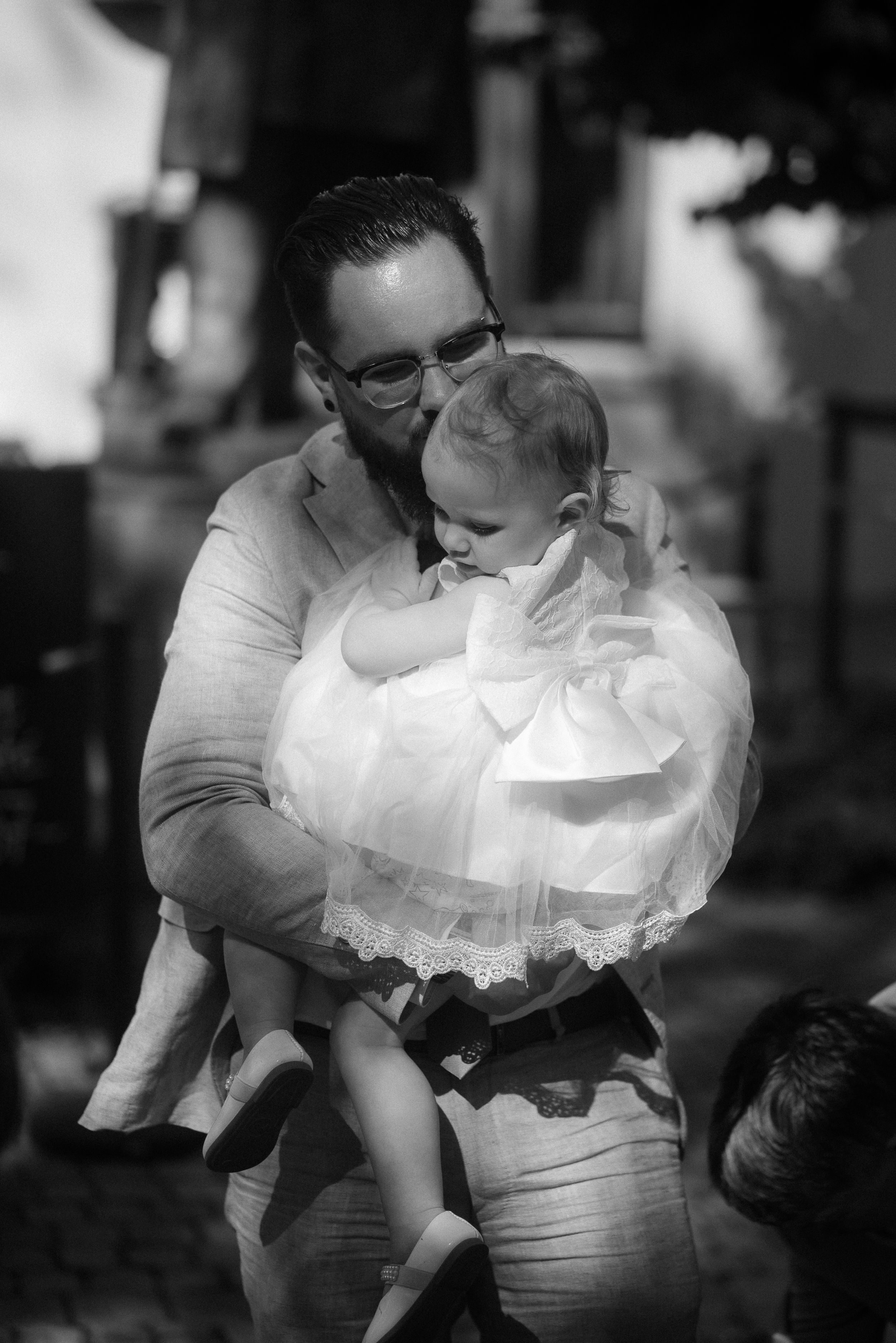 A tender moment captured between parent and child in formal white attire.