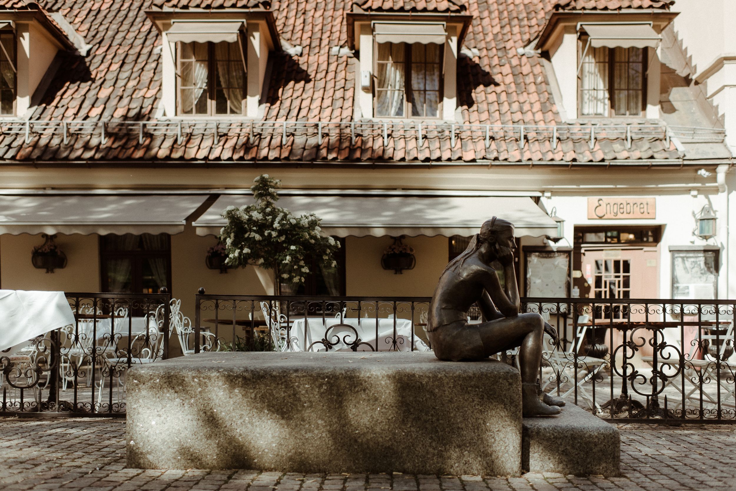 Historic cafe terrace with clay tile roof and ornate wrought iron railing details.