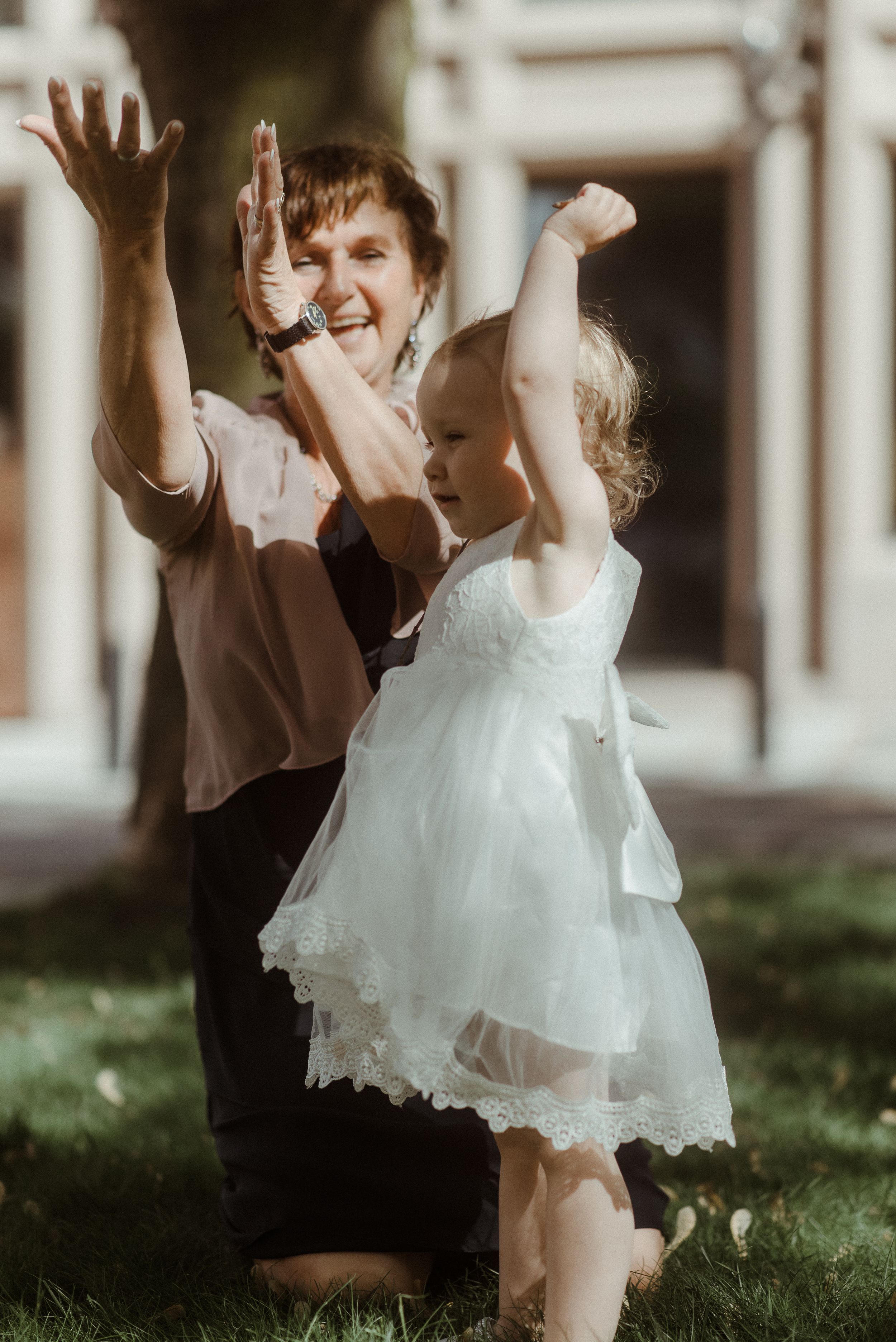 Two figures in casual attire and formal wear share an enthusiastic high-five outdoors.