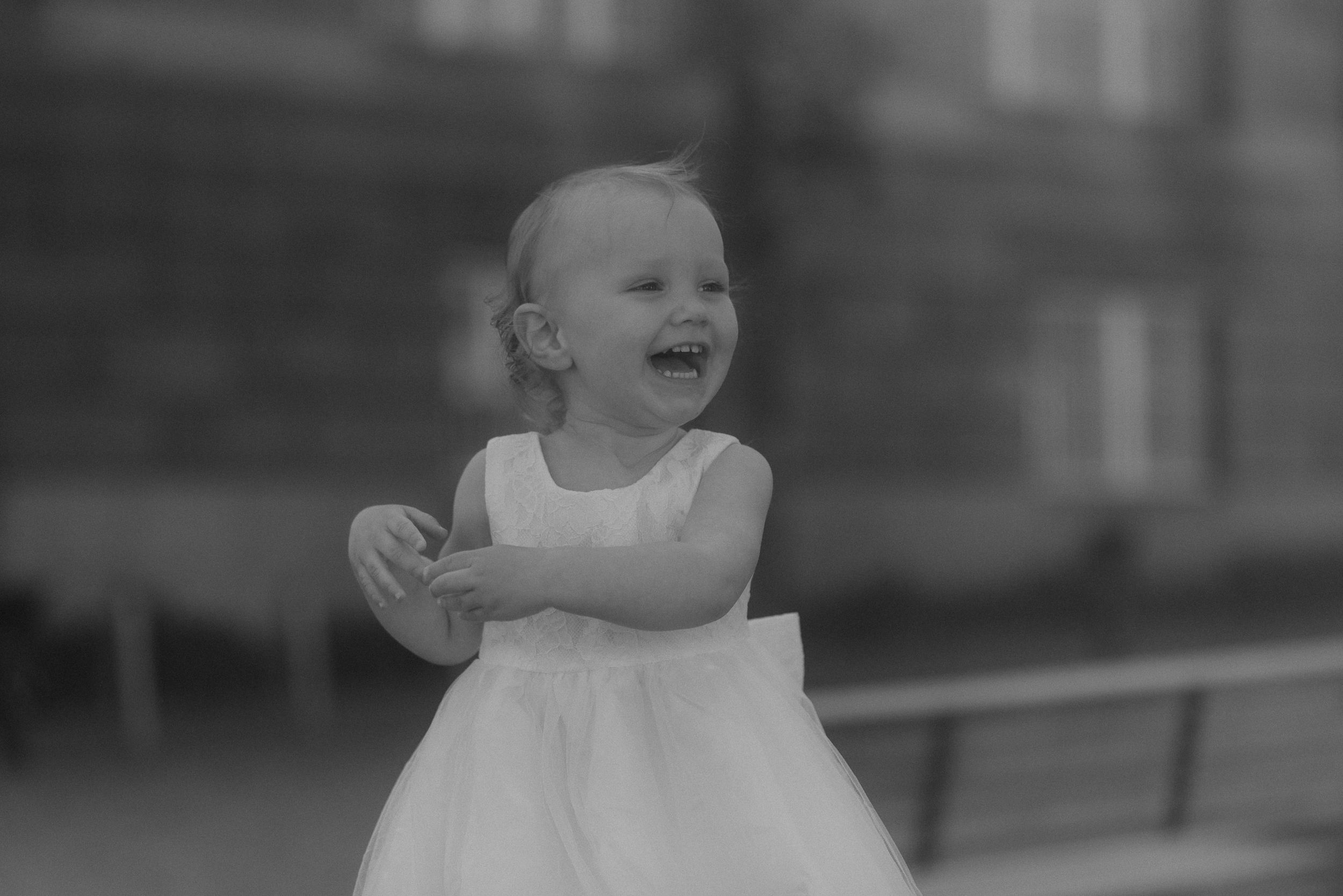 A joyful figure in a white dress laughs while standing outdoors.