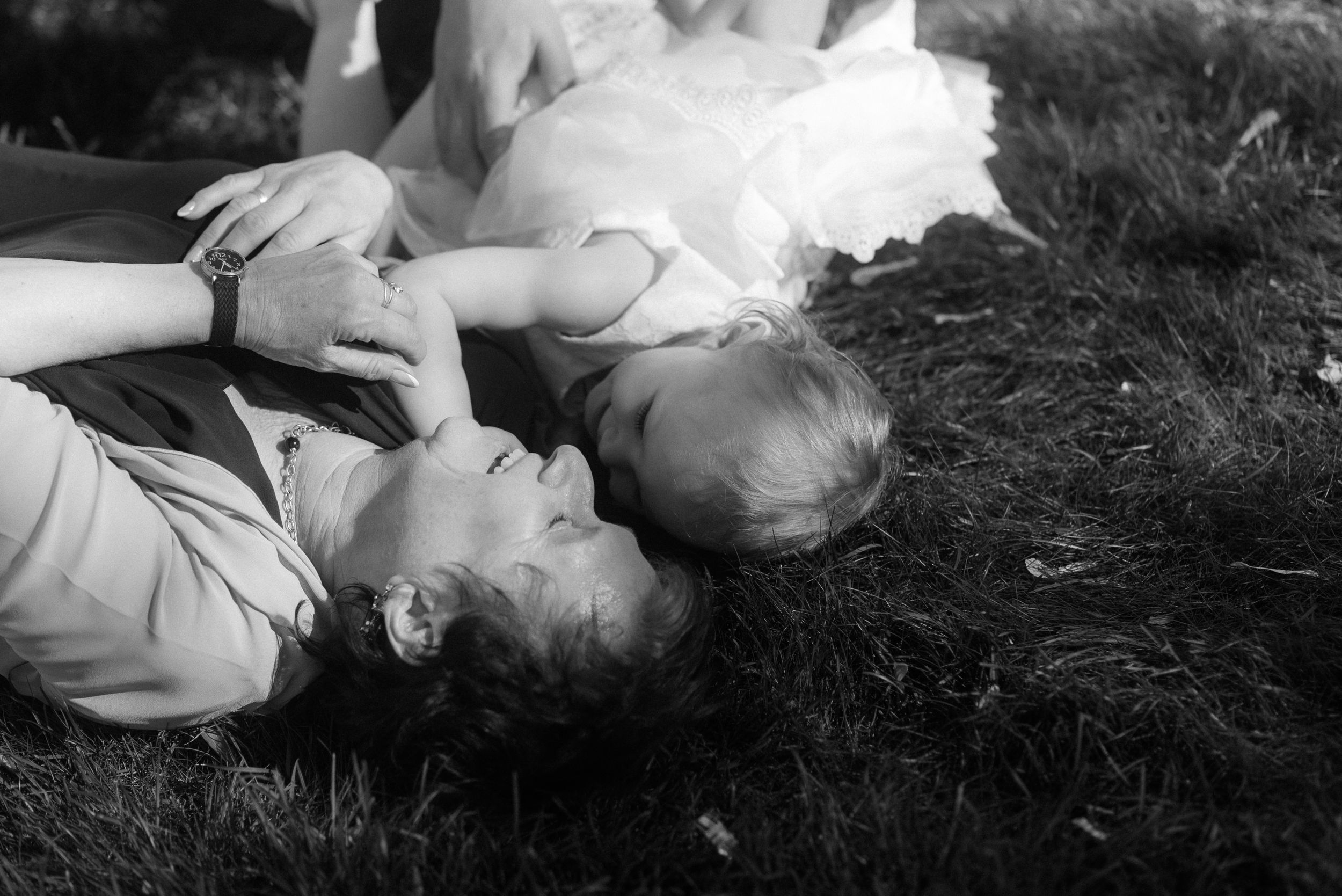 Two people lying in grass together on a sunny day captured in black and white.