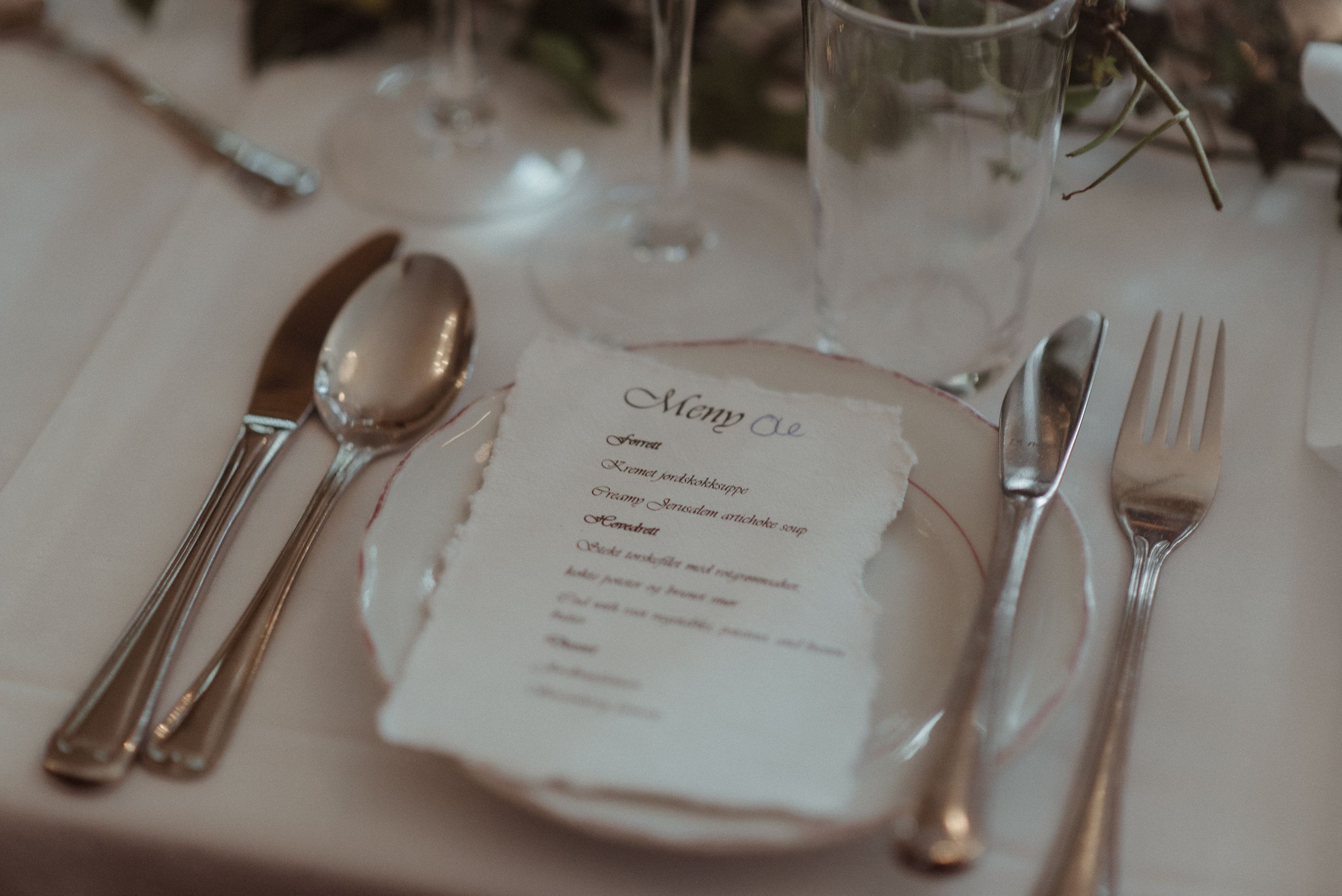 An elegant place setting with silverware and menu card at formal dinner table.