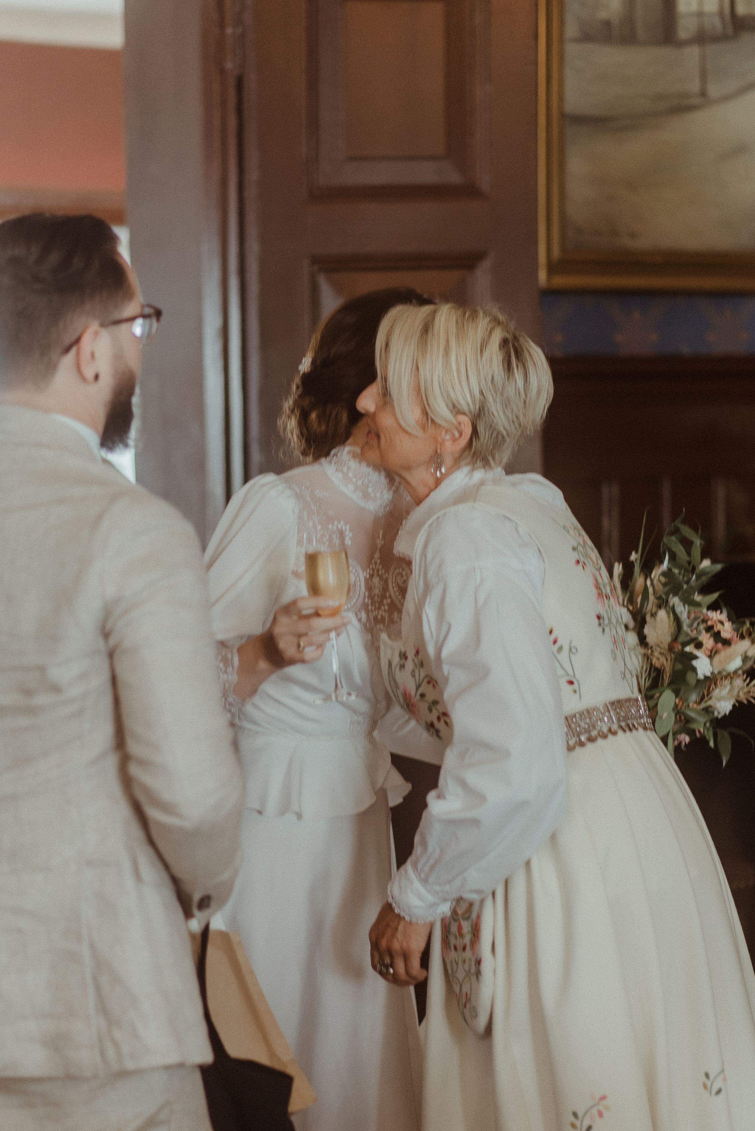 Intimate gathering of guests in white attire at an elegant indoor celebration.