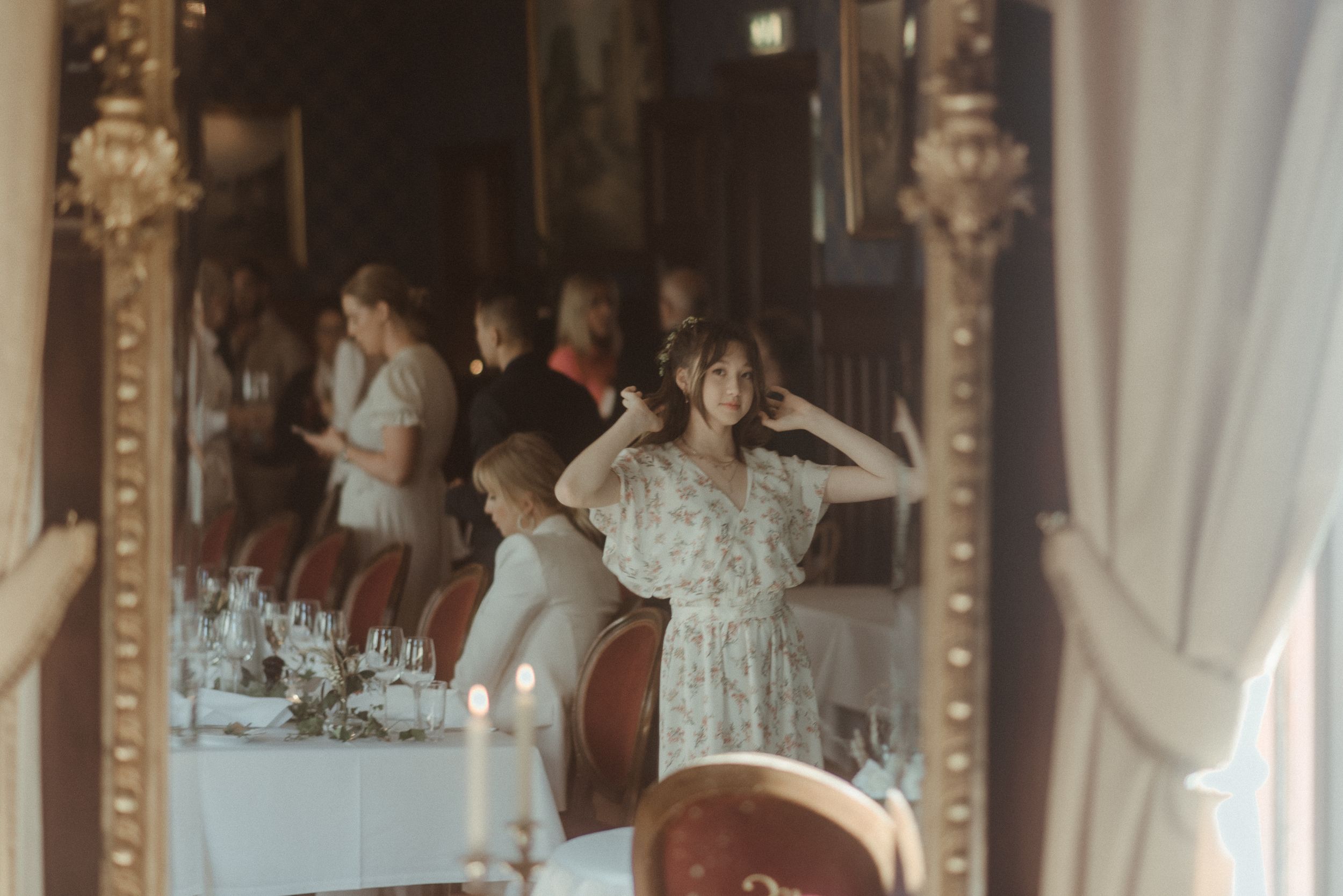 Guests enjoying a celebration in an elegant dining room with ornate mirrors and vintage decor.