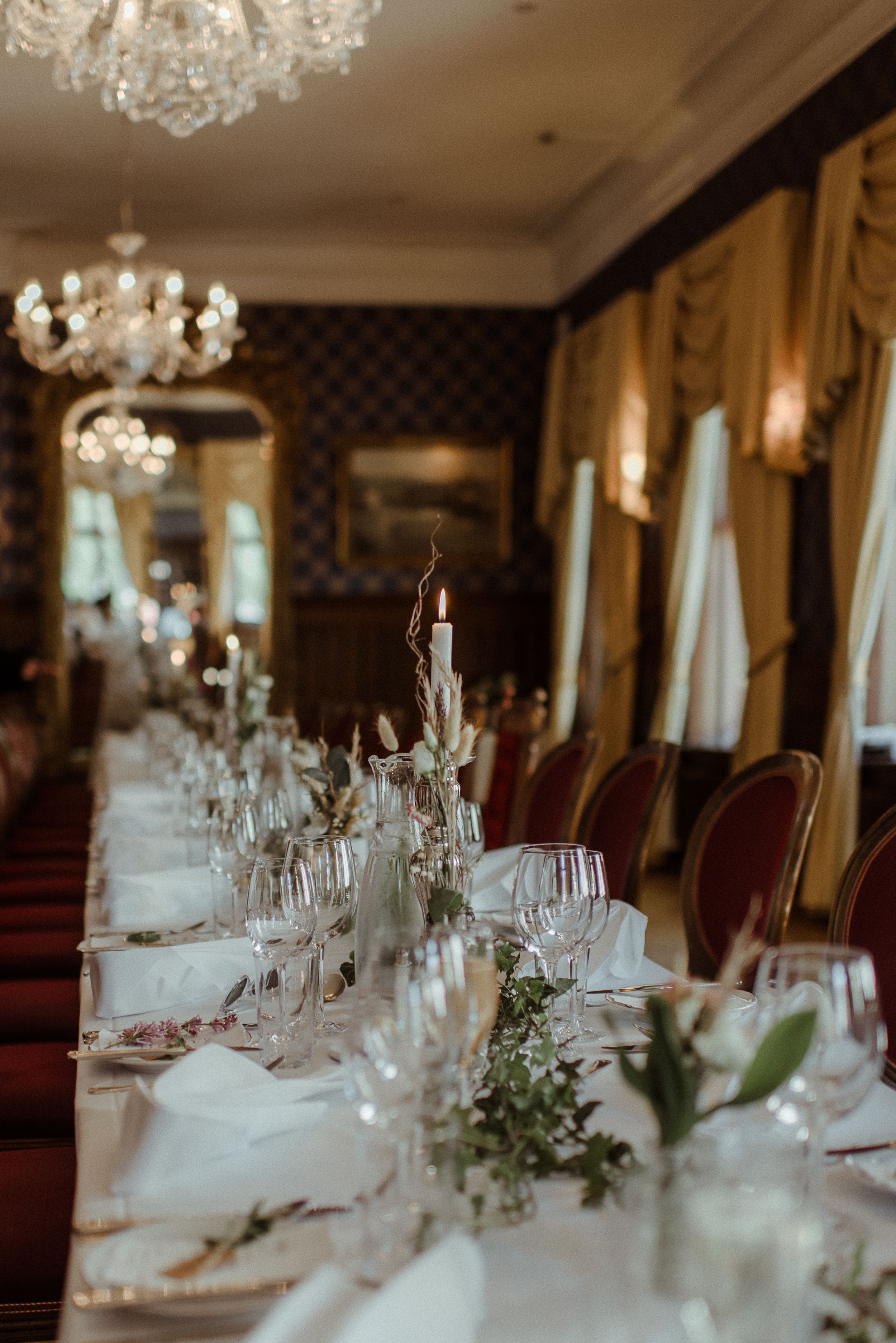 Elegant table setting with crystal chandeliers and floral centerpieces in a luxury dining room.