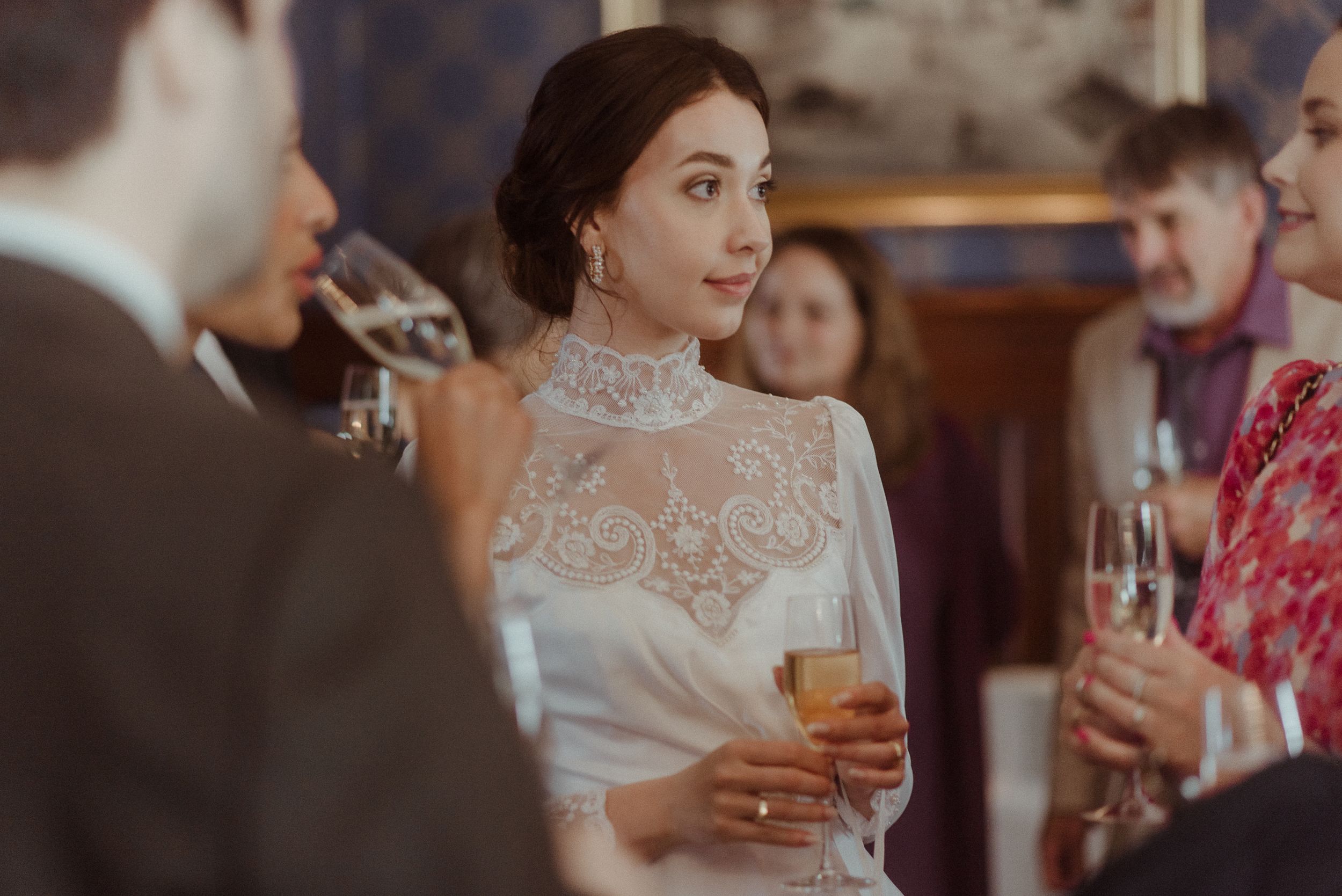 Elegant wedding reception gathering with formal attire and champagne glasses in an indoor venue.