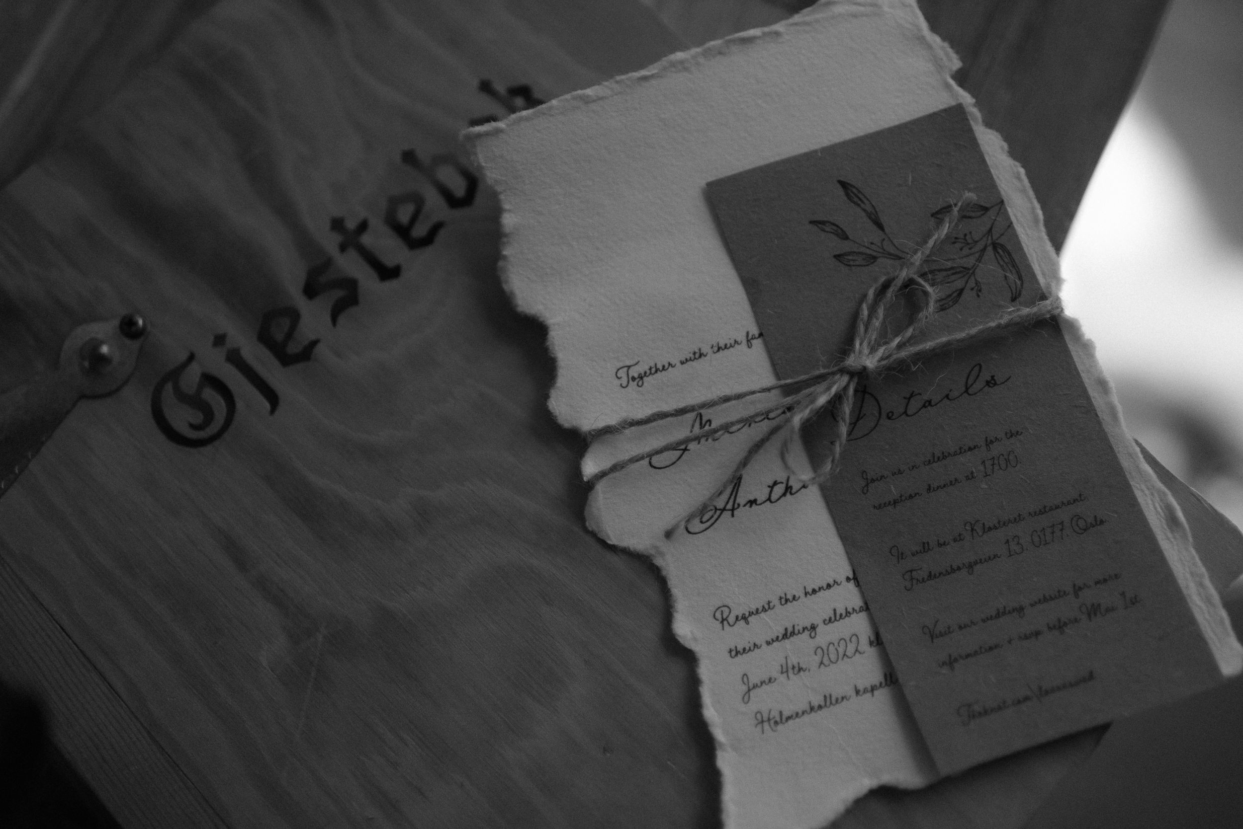 Vintage-style wedding invitation with torn edges and ribbon in black and white.