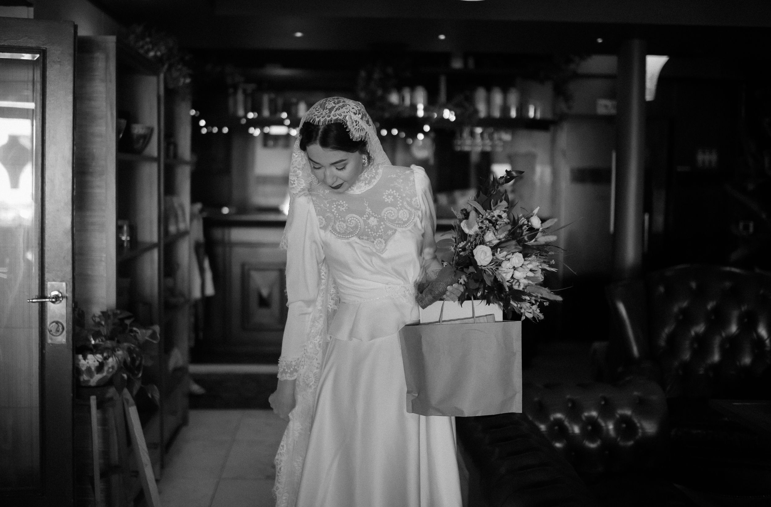 Classic black and white portrait of bride holding floral arrangement indoors.
