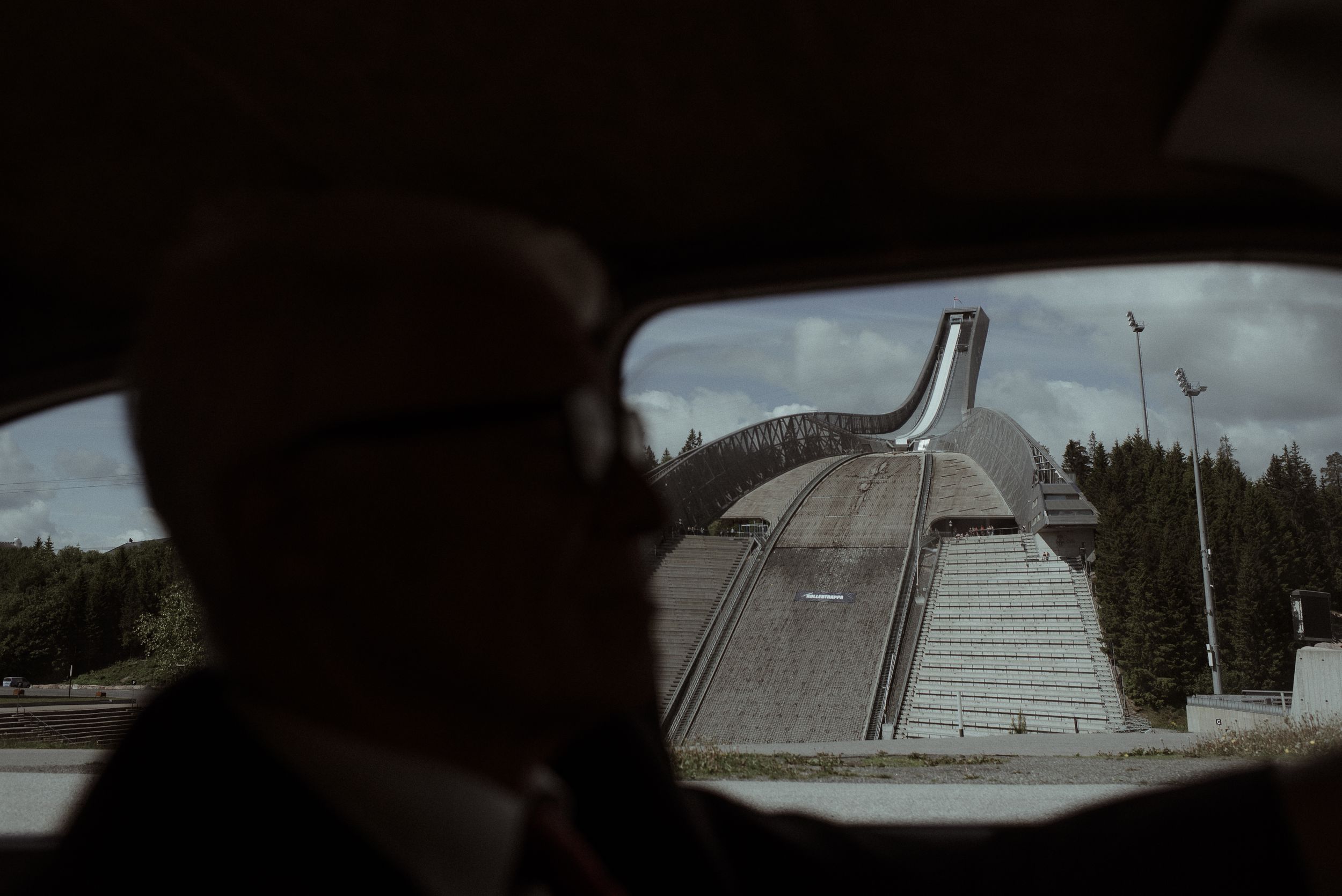 Modern architectural dome structure viewed through a car window against a cloudy sky.