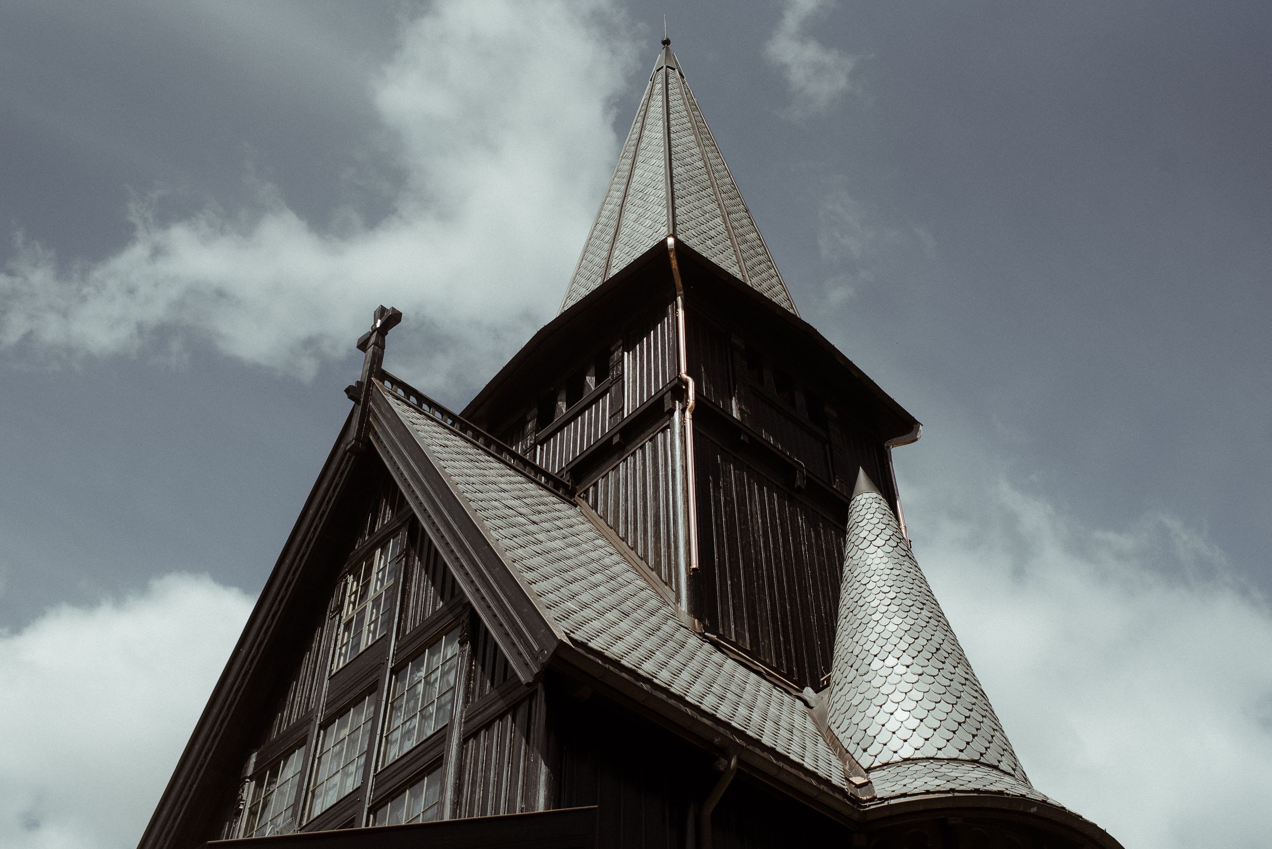 Dramatic upward view of a wooden church steeple with angular architectural details.