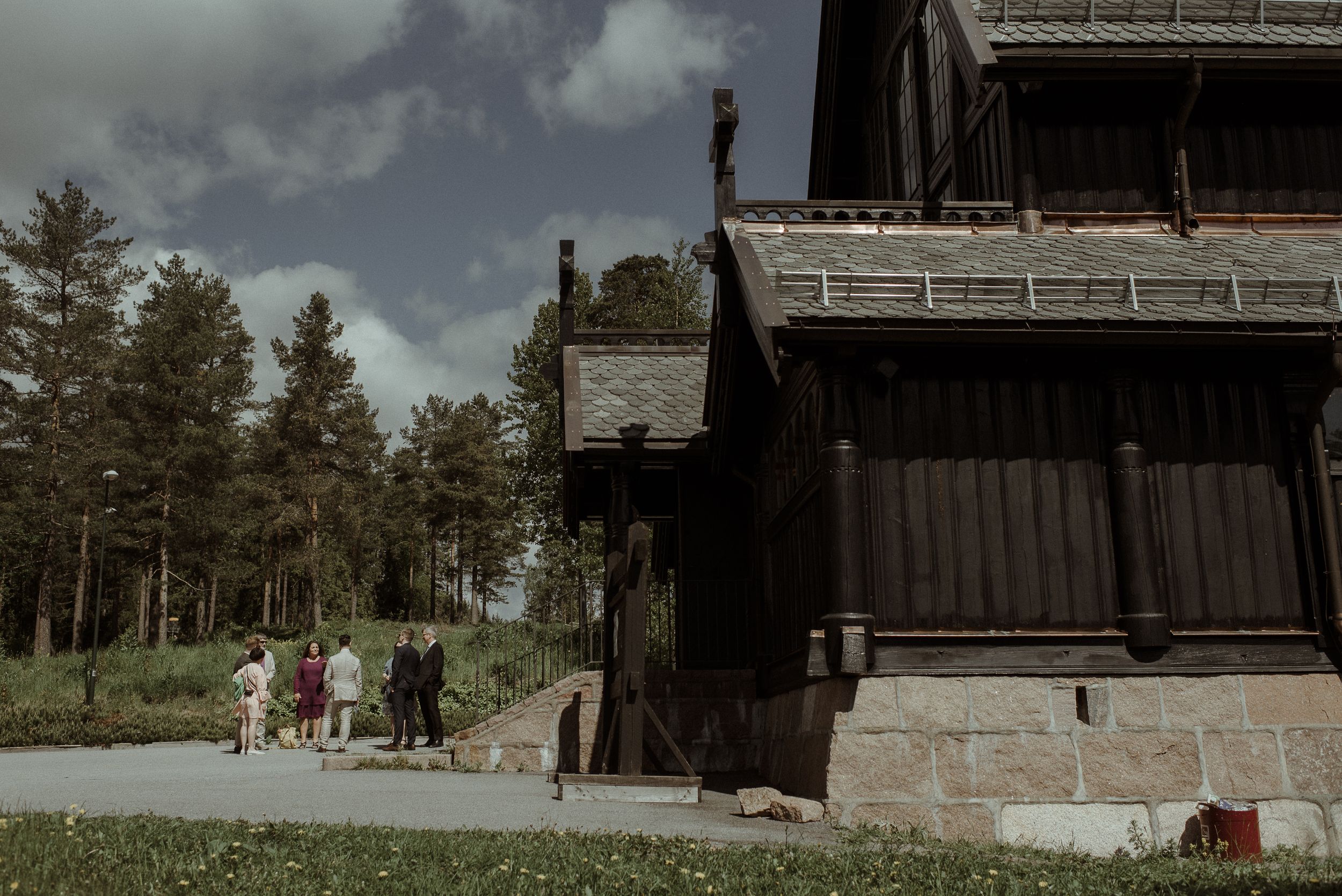 Historic wooden church building surrounded by evergreen trees on a summer day.