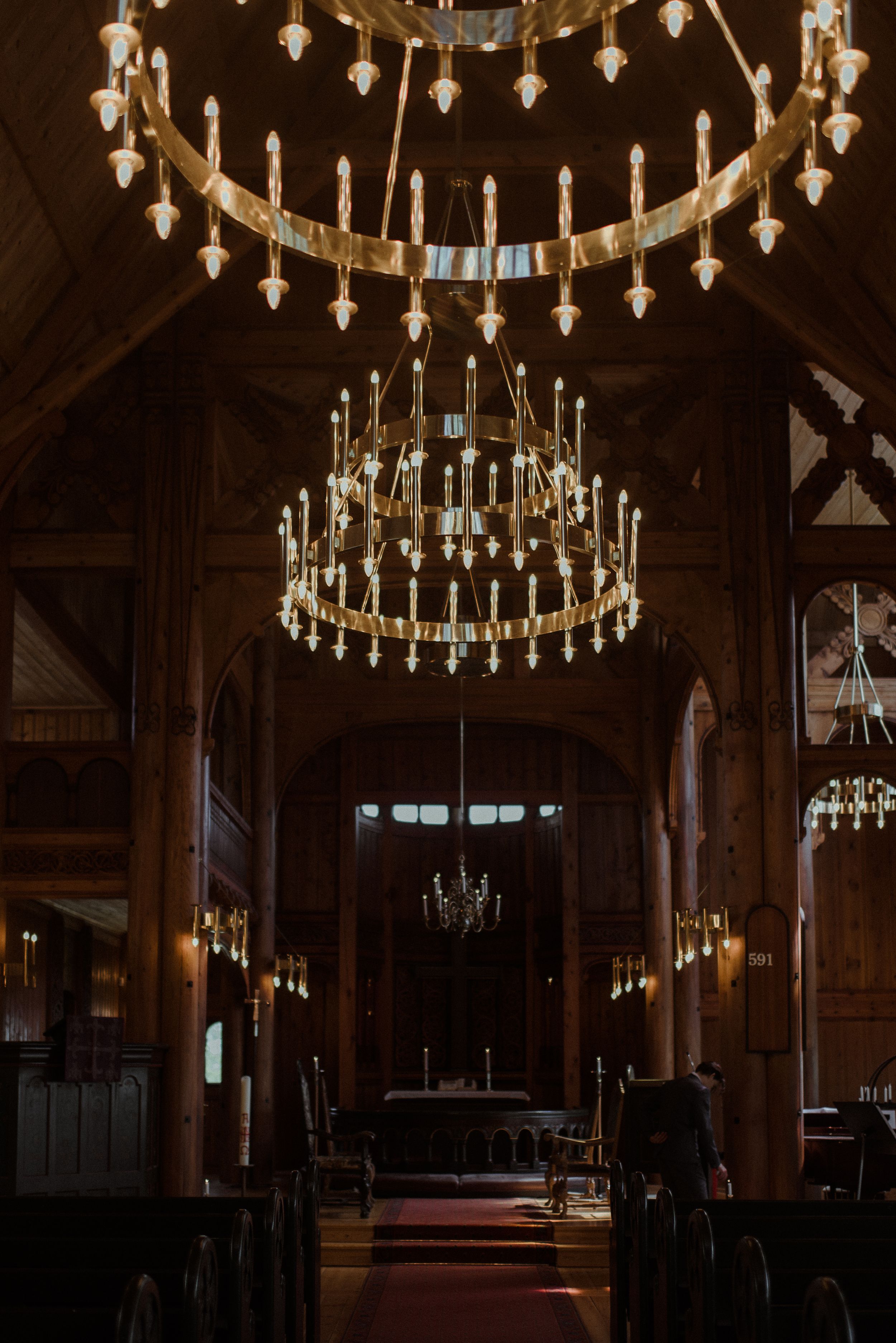 Ornate chandelier lighting inside a grand wooden church sanctuary.