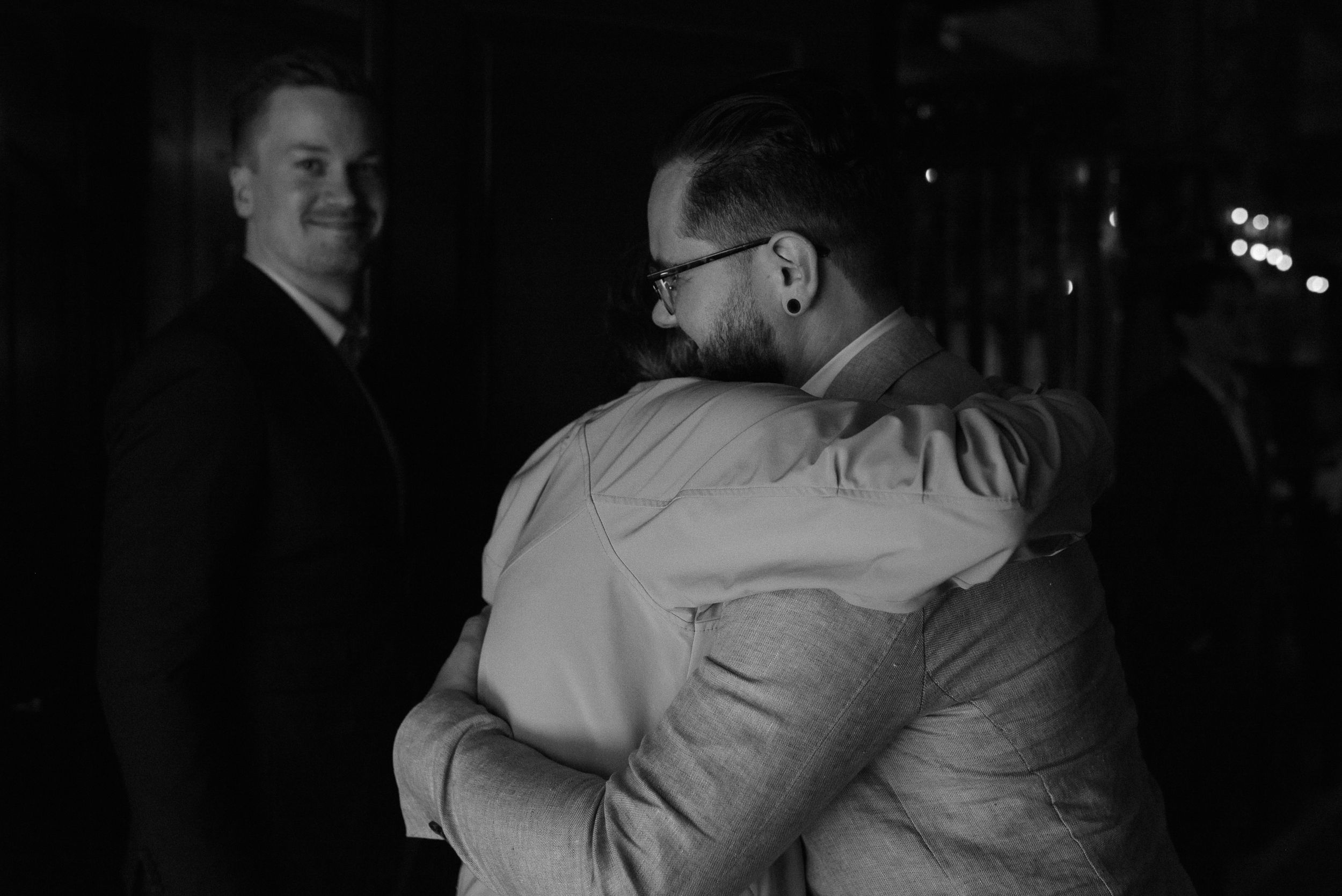 Black and white photograph showing an intimate moment at an indoor gathering.