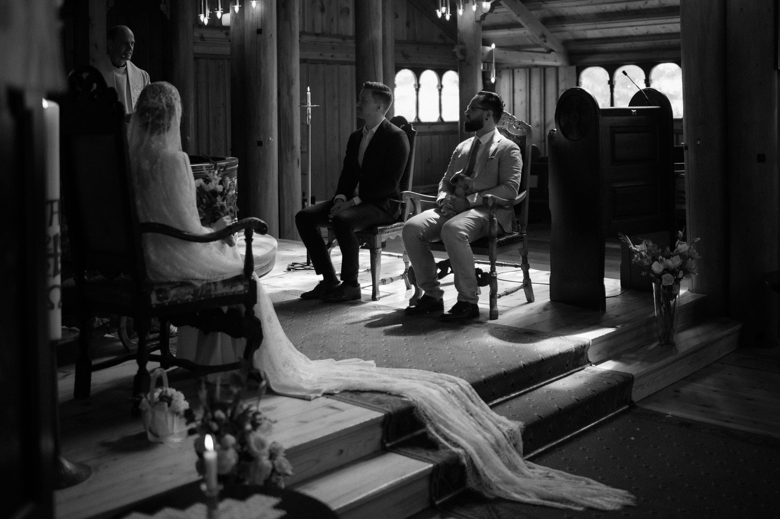 A black and white wedding ceremony photo showing guests seated in an ornate church interior.